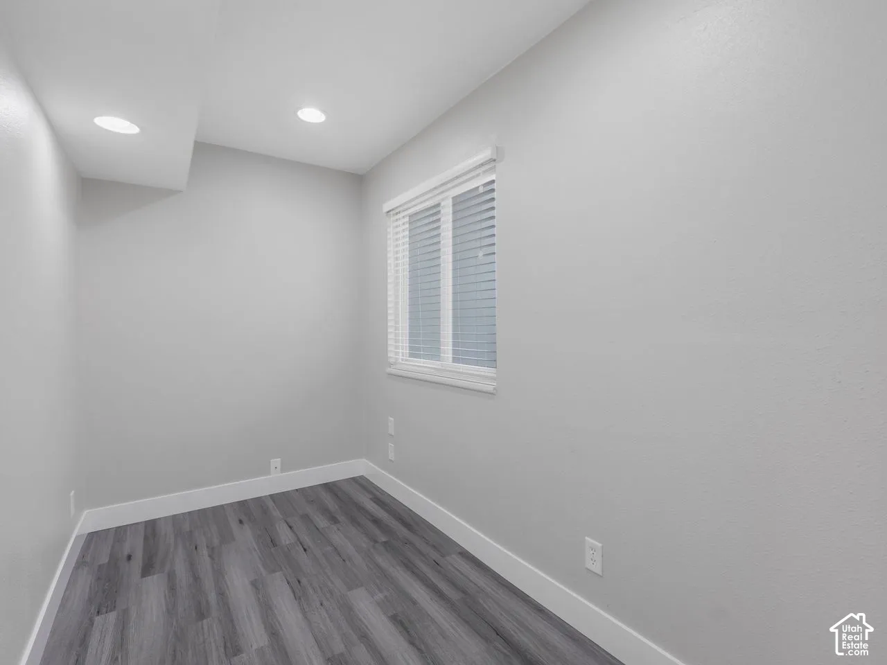 Room featuring wood-finish flooring, recessed lighting, and a single window with horizontal blinds