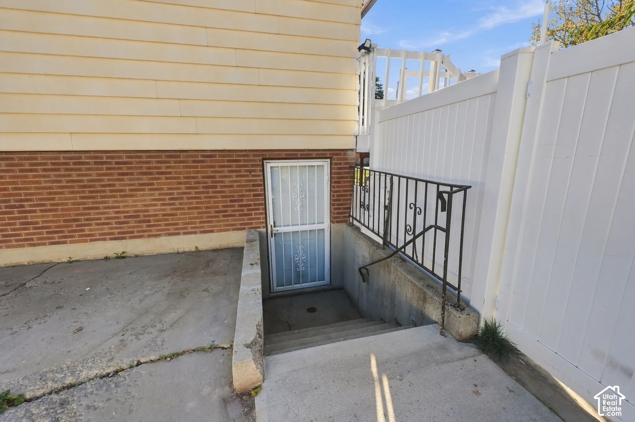 Exterior stairwell to a lower-level entrance with security door and iron handrail
