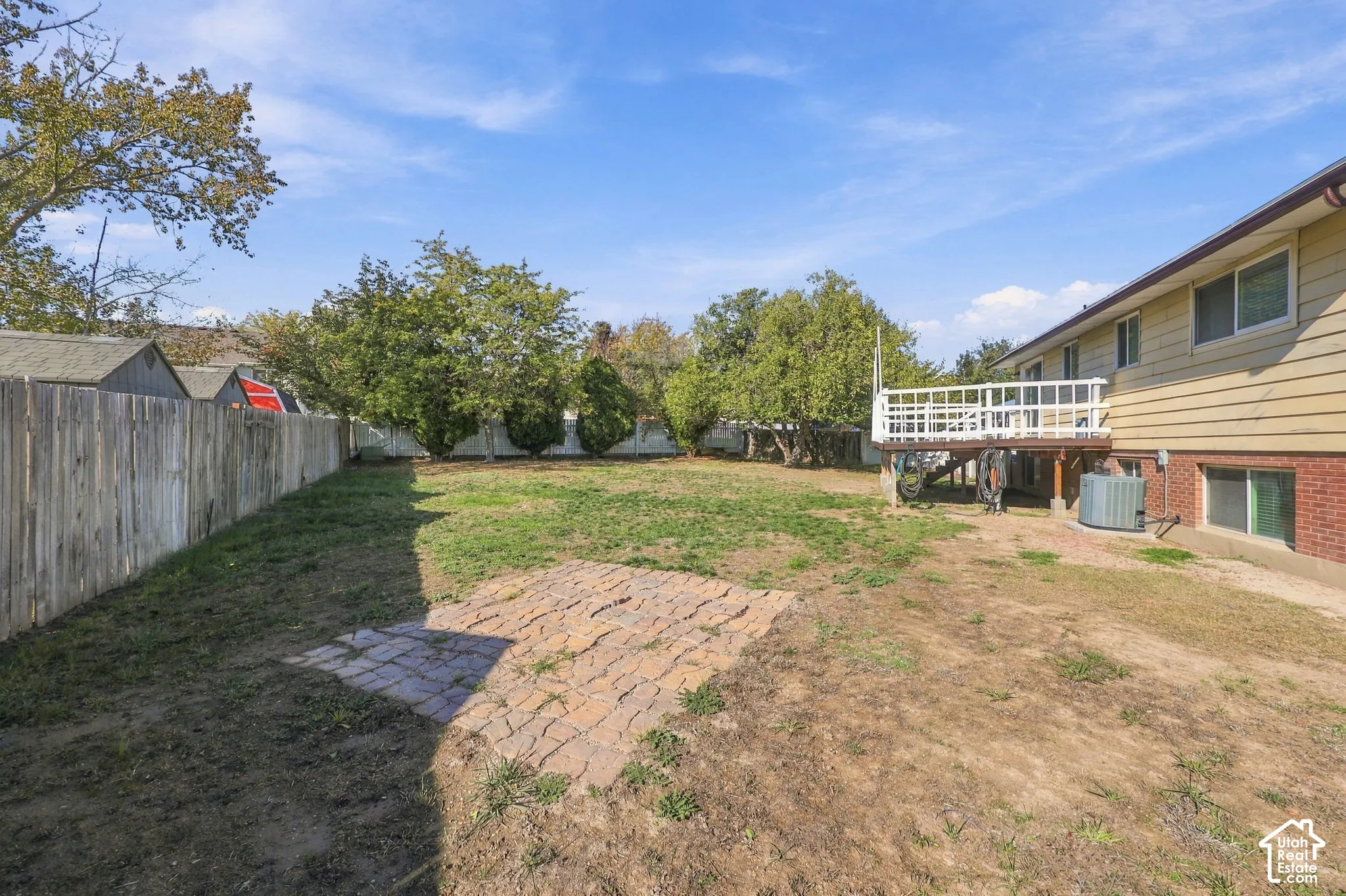 Backyard with paver patio, wood privacy fencing, mature trees, and elevated deck