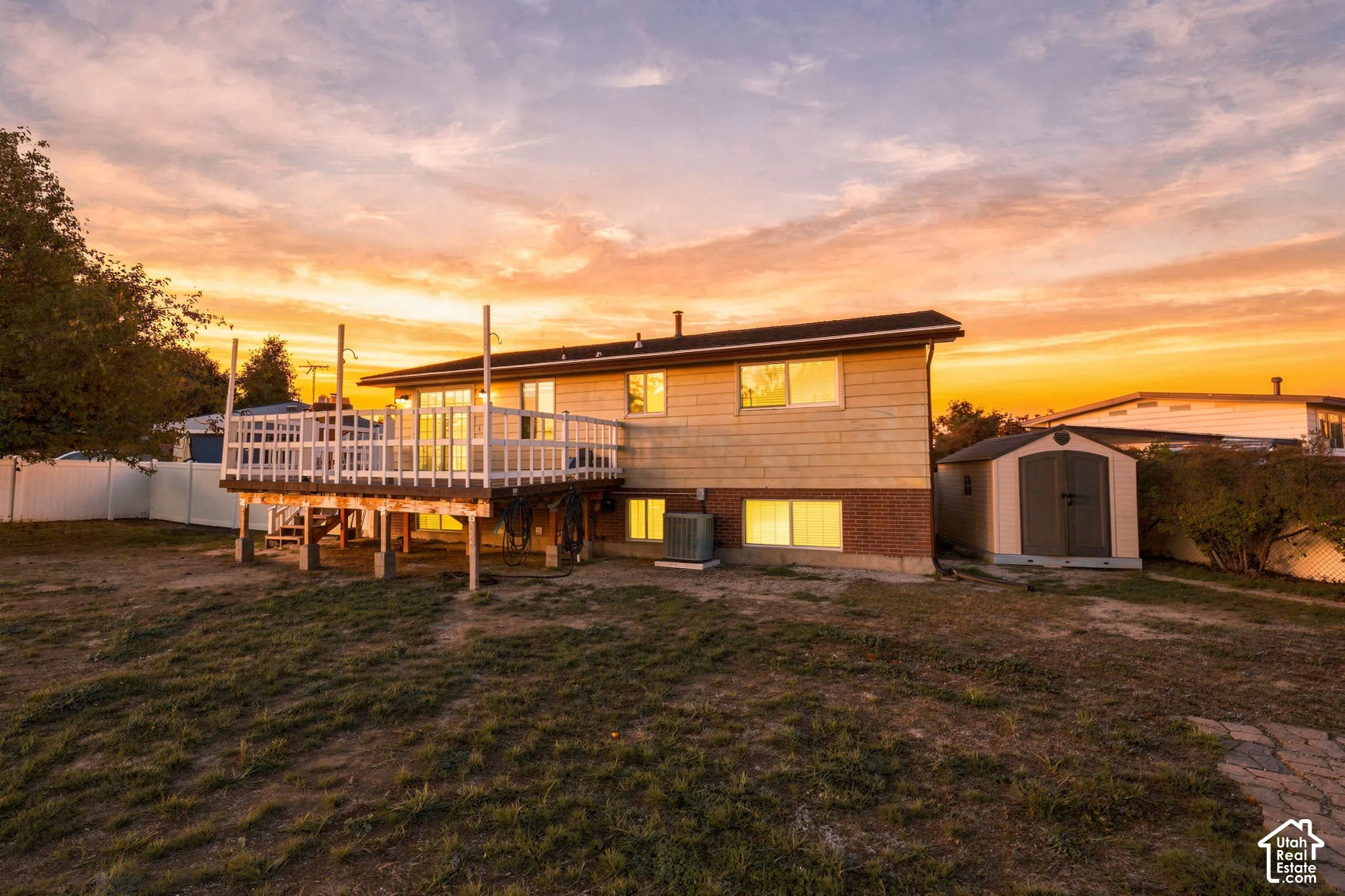Rear exterior with elevated wood deck, brick and siding, and detached storage shed