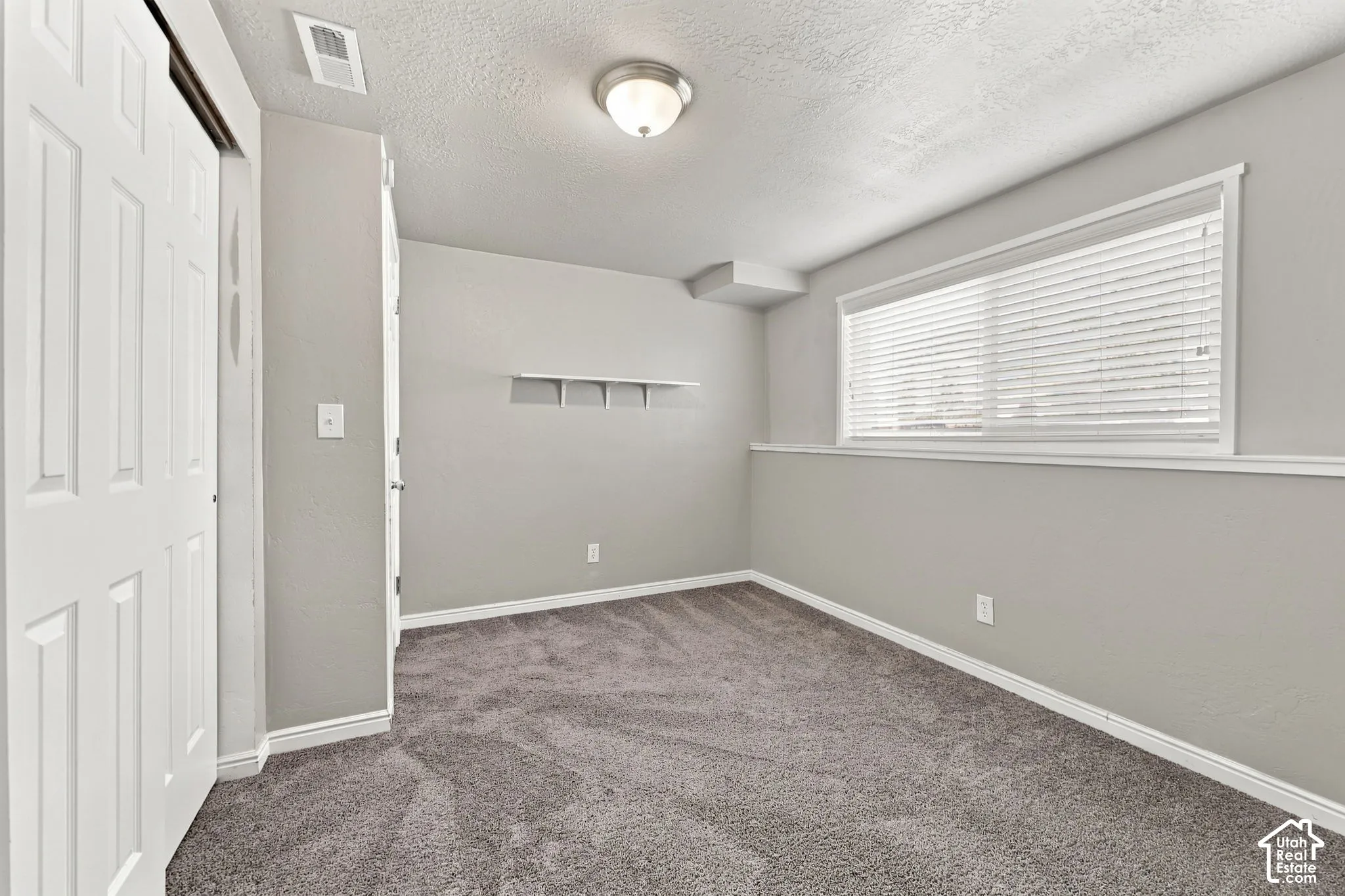 Bedroom with carpet, closet, chair rail, and window with blinds