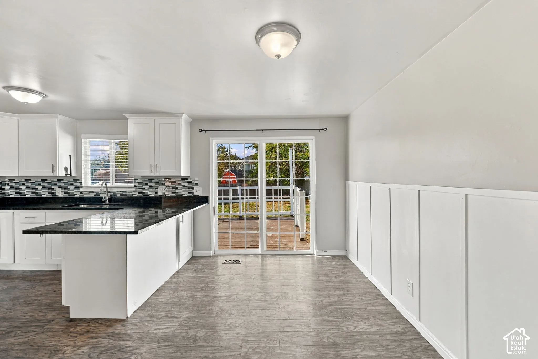 Kitchen and dining area with wood-look flooring, wainscoting, and sliding glass door to the deck
