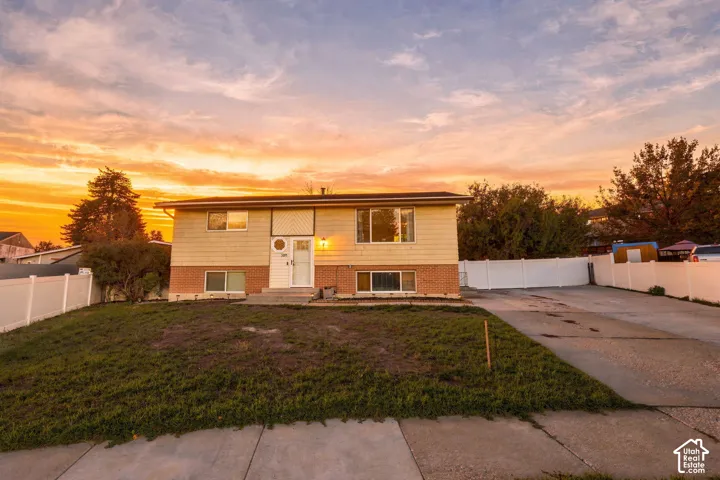 Front exterior of the split-level home with brick and siding, concrete driveway, and white vinyl fencing