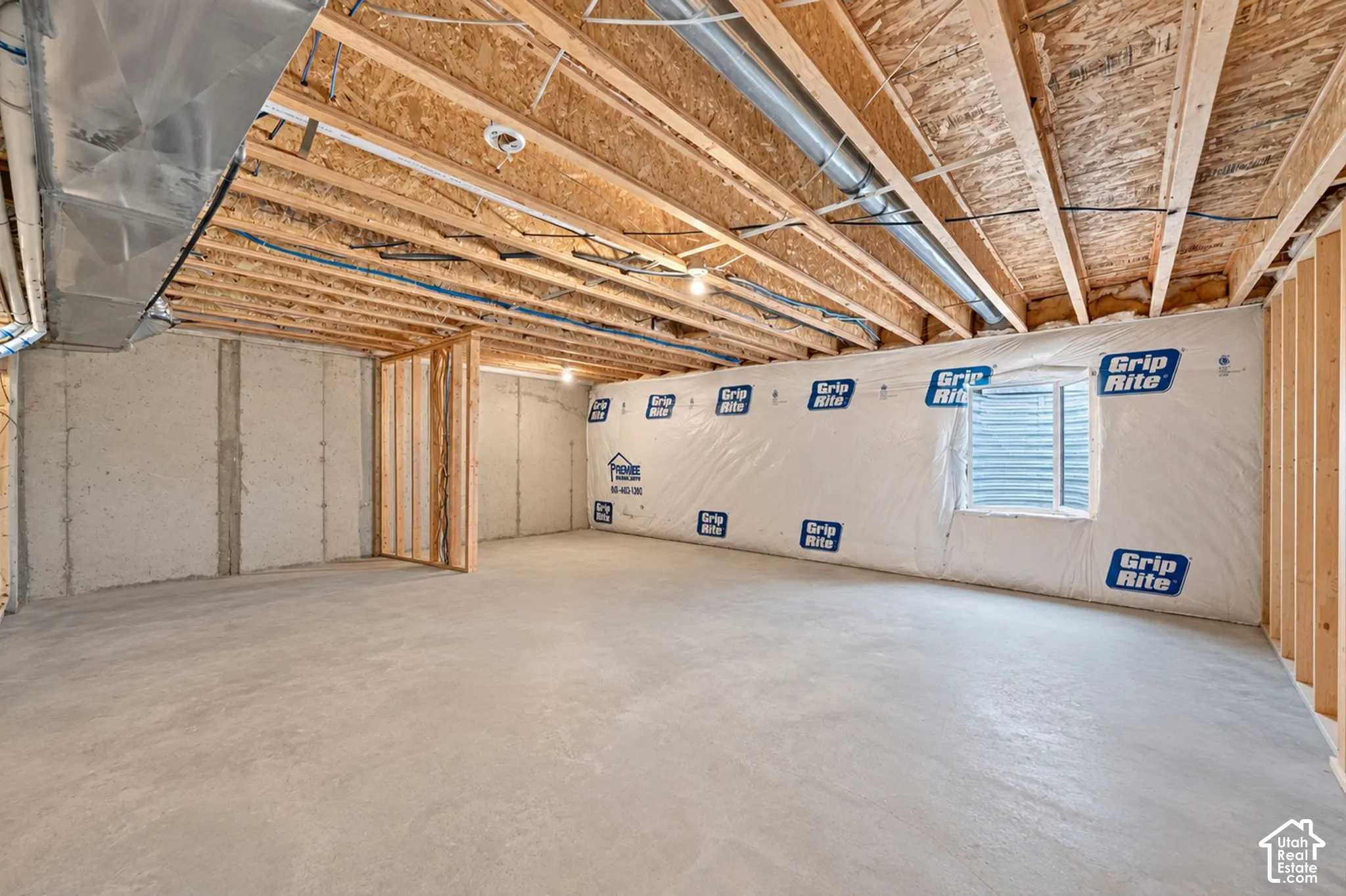 Unfinished lower level featuring exposed wood joist ceilings, concrete foundation walls, stud-framed wall partitions, and an egress window
