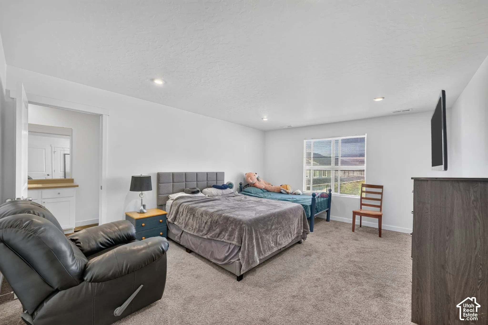 Spacious room featuring neutral carpeting, recessed lighting, and a large window