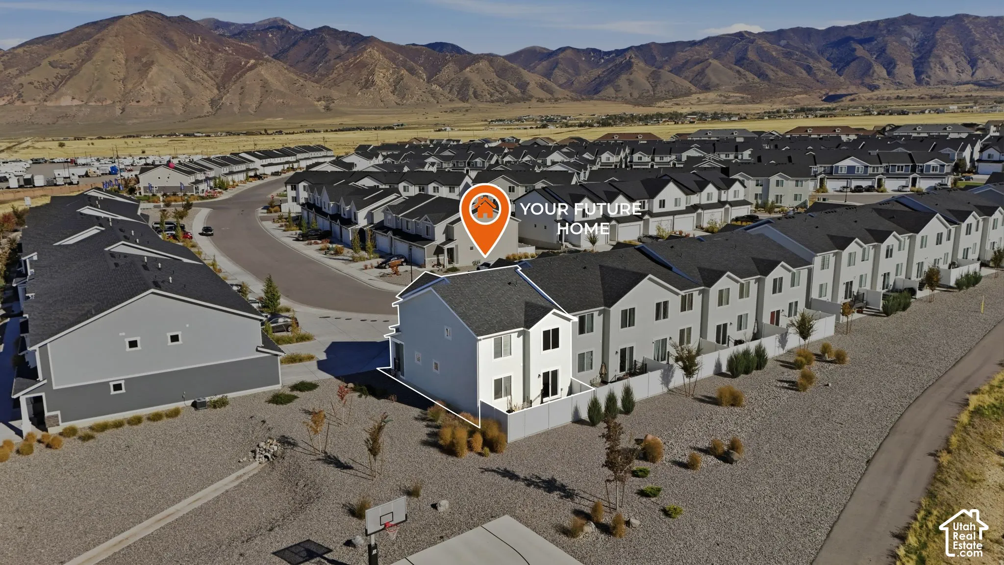 Aerial perspective of two-story residence featuring light-toned siding, pitched roofline, enclosed private patio area, and prominent mountain backdrop