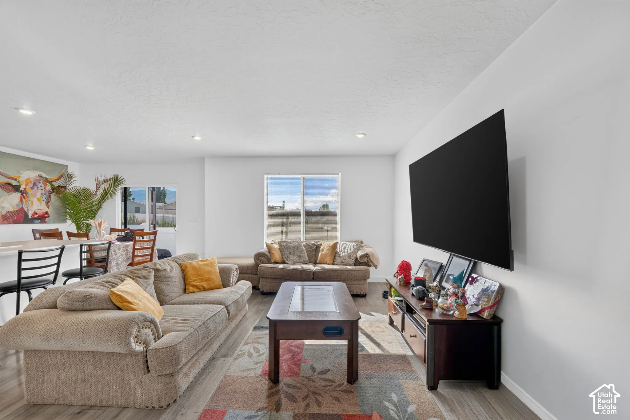 Open-concept living space featuring wood-finish flooring, recessed lighting, and a neutral color palette