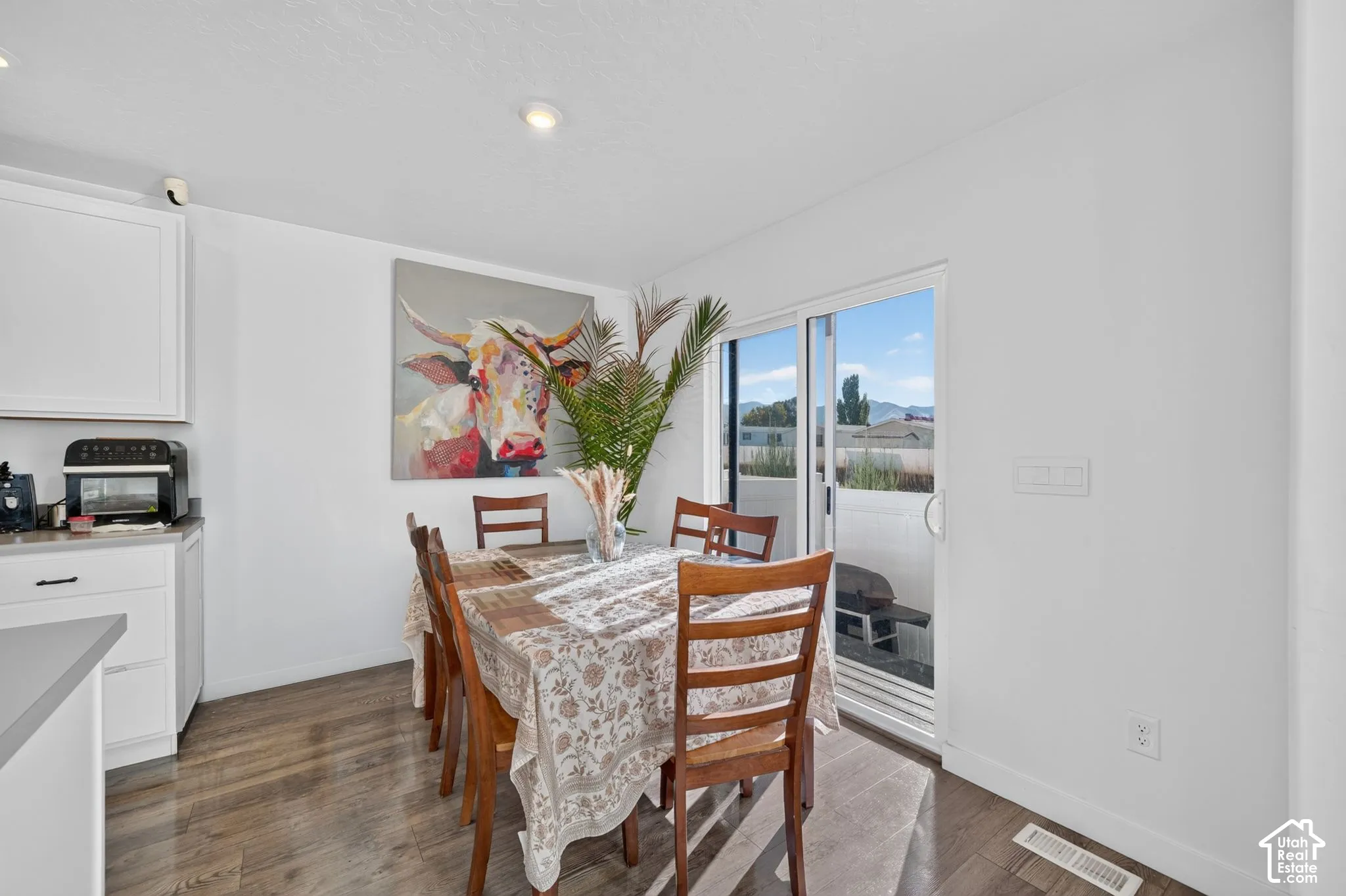 Dining area featuring wood-finish flooring, white cabinetry, recessed lighting, and a sliding glass door providing access to the exterior