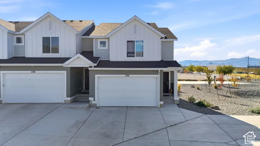 Two-story exterior featuring board-and-batten siding, attached two-car garages, concrete driveway, and mountain backdrop