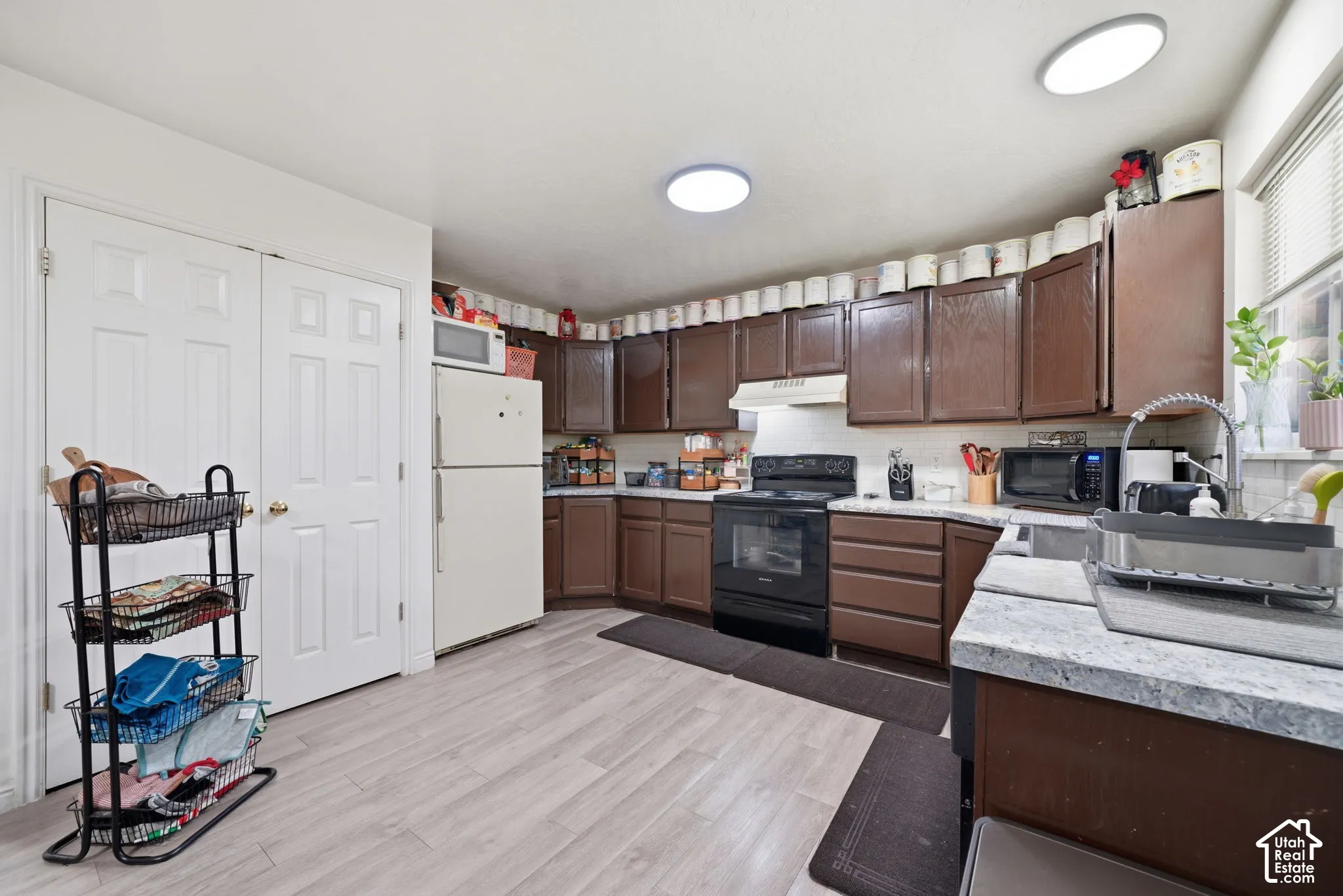 Kitchen featuring wood-finish cabinetry, stone-patterned laminate countertops, light-toned wood-finish flooring, and dual flush-mount ceiling light fixtures