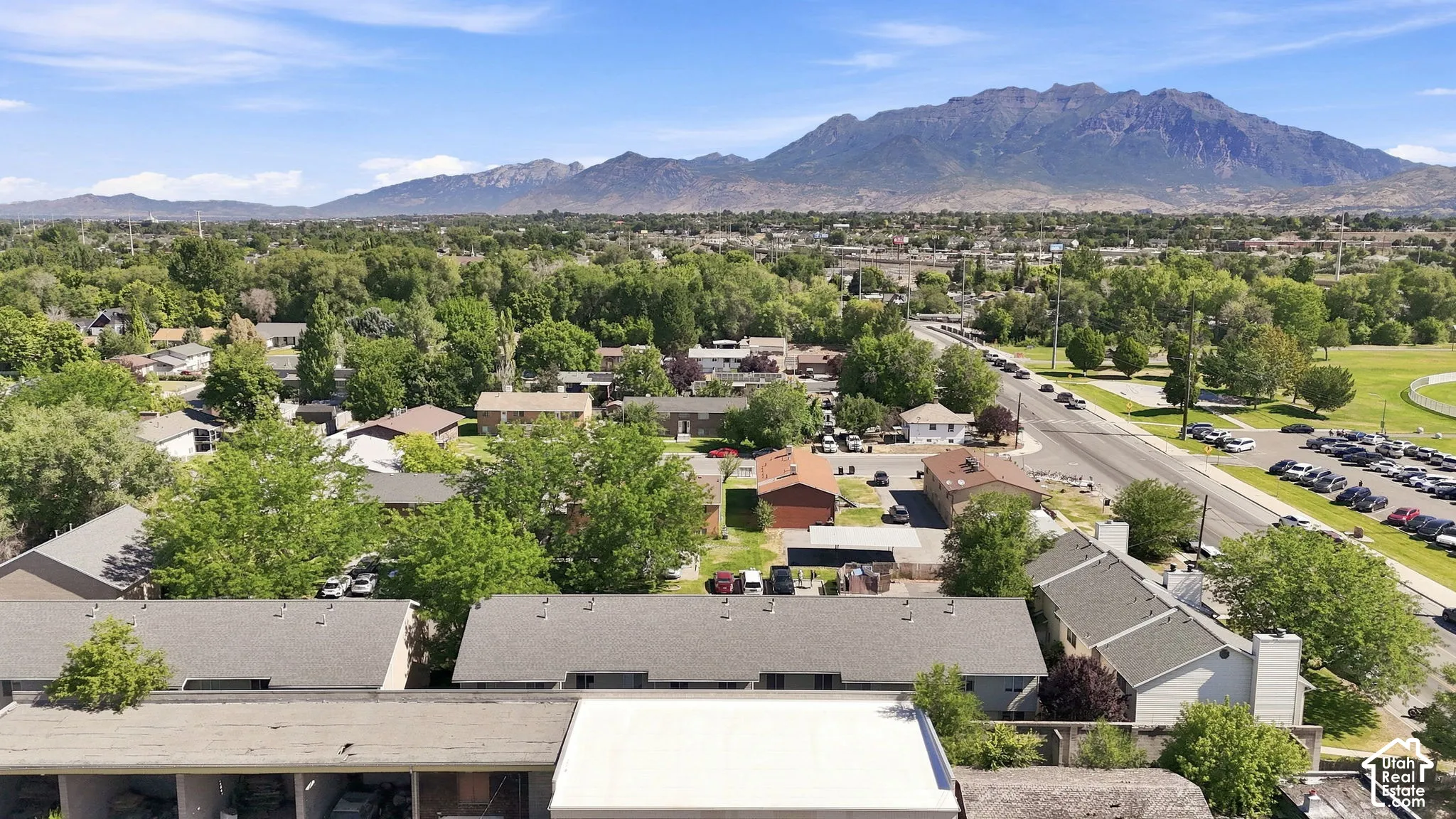 Aerial perspective featuring expansive mountain range backdrop and mature tree canopy throughout the surrounding area
