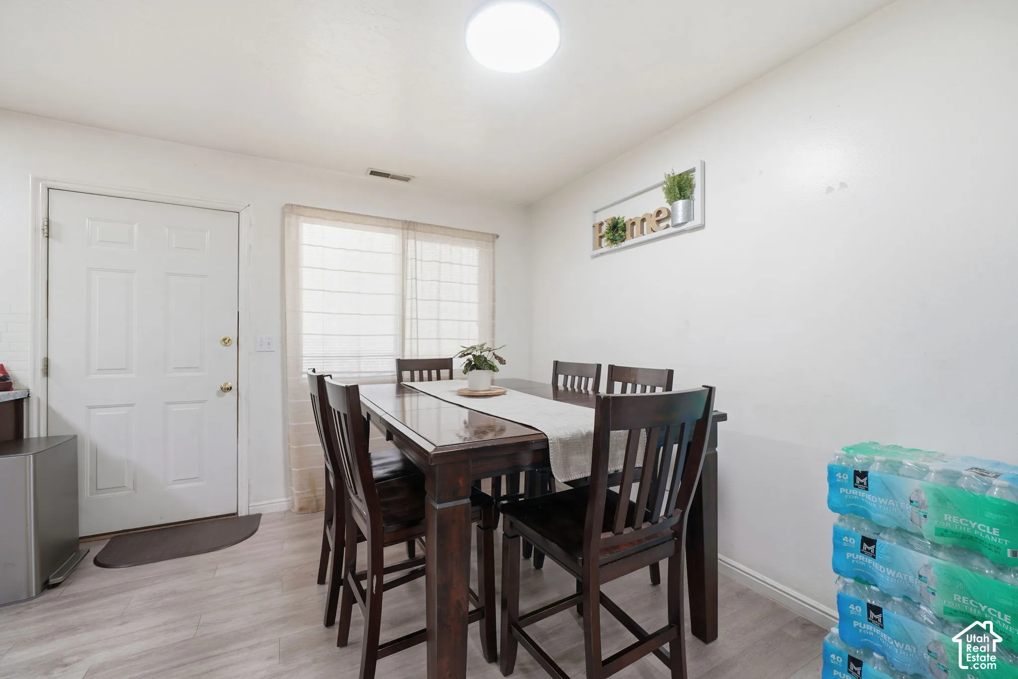 Neutral-toned wood-finish flooring, sliding window with sheer window treatments, and flush-mount ceiling lighting