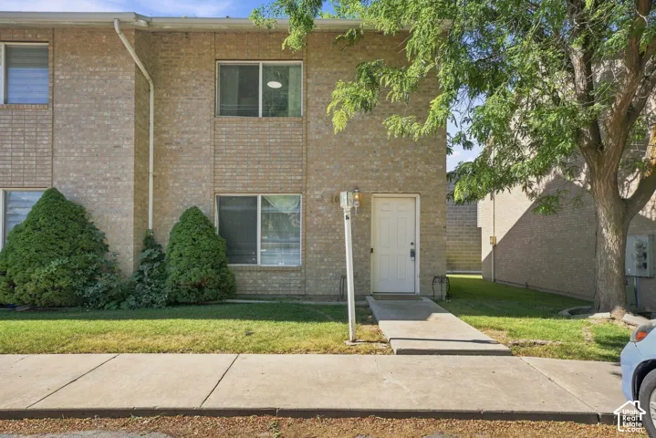 Multi-level brick exterior featuring a concrete walkway, mature landscaping, and sliding-frame windows
