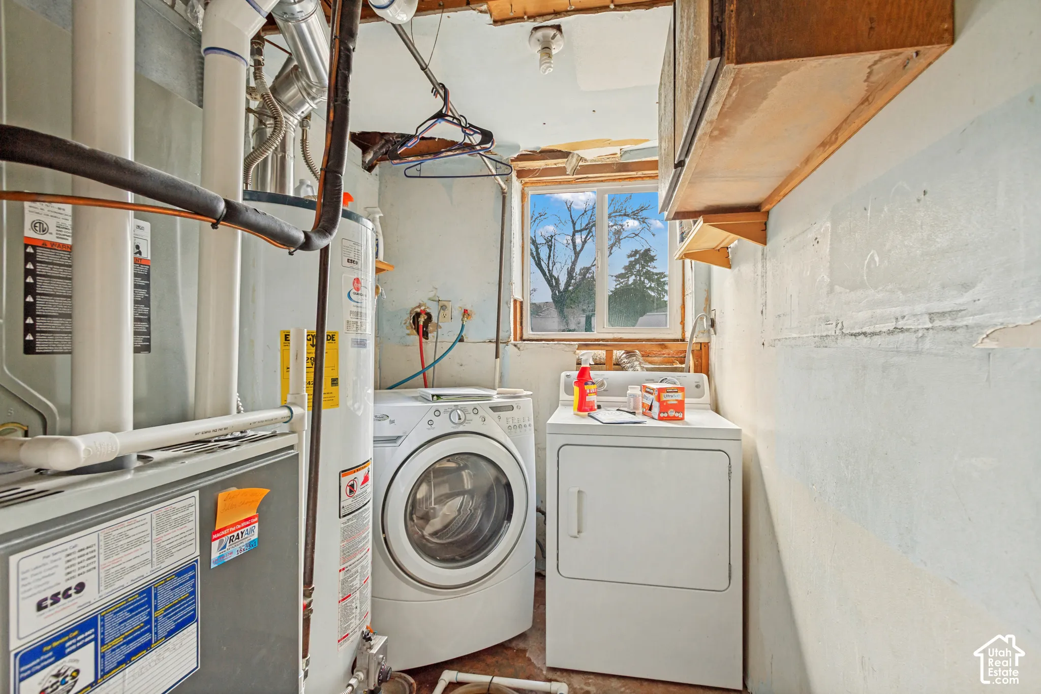 Utility area featuring a central water heater, furnace unit, and single-pane sliding window
