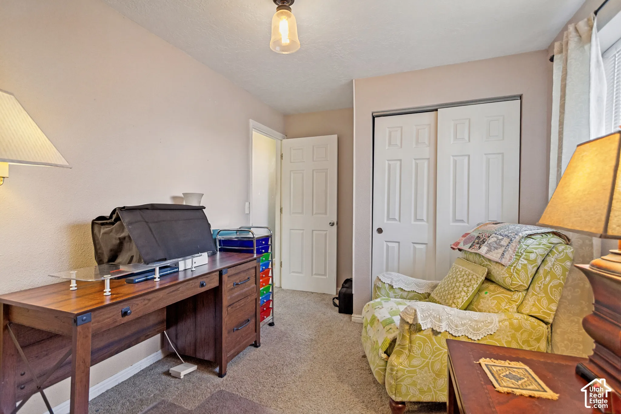 Room featuring neutral-toned walls, carpeted flooring, a ceiling-mounted pendant light fixture, a six-panel interior door, and a sliding-door closet