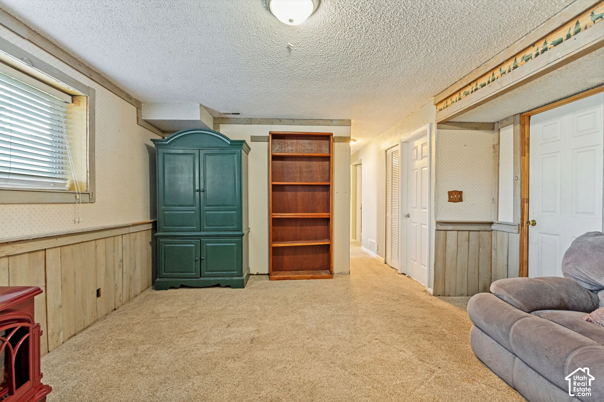 Interior space featuring wood panel wainscoting, a built-in recessed shelving unit, neutral carpeting, and multi-panel interior doors