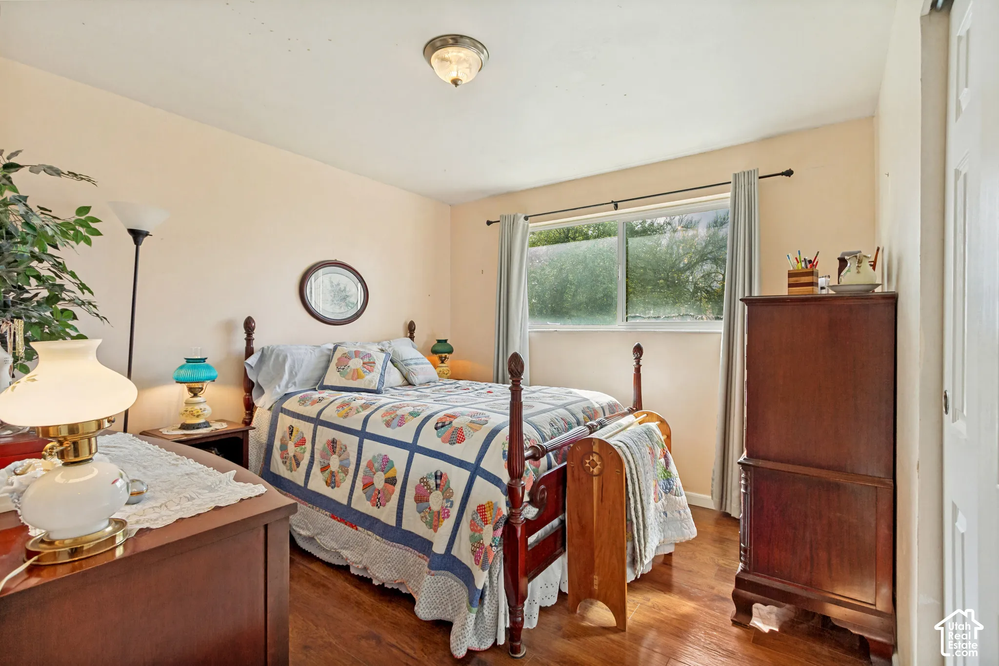 Bedroom featuring wood-finish flooring, a ceiling-mounted light fixture, and a large horizontal sliding window with metal-finish hardware