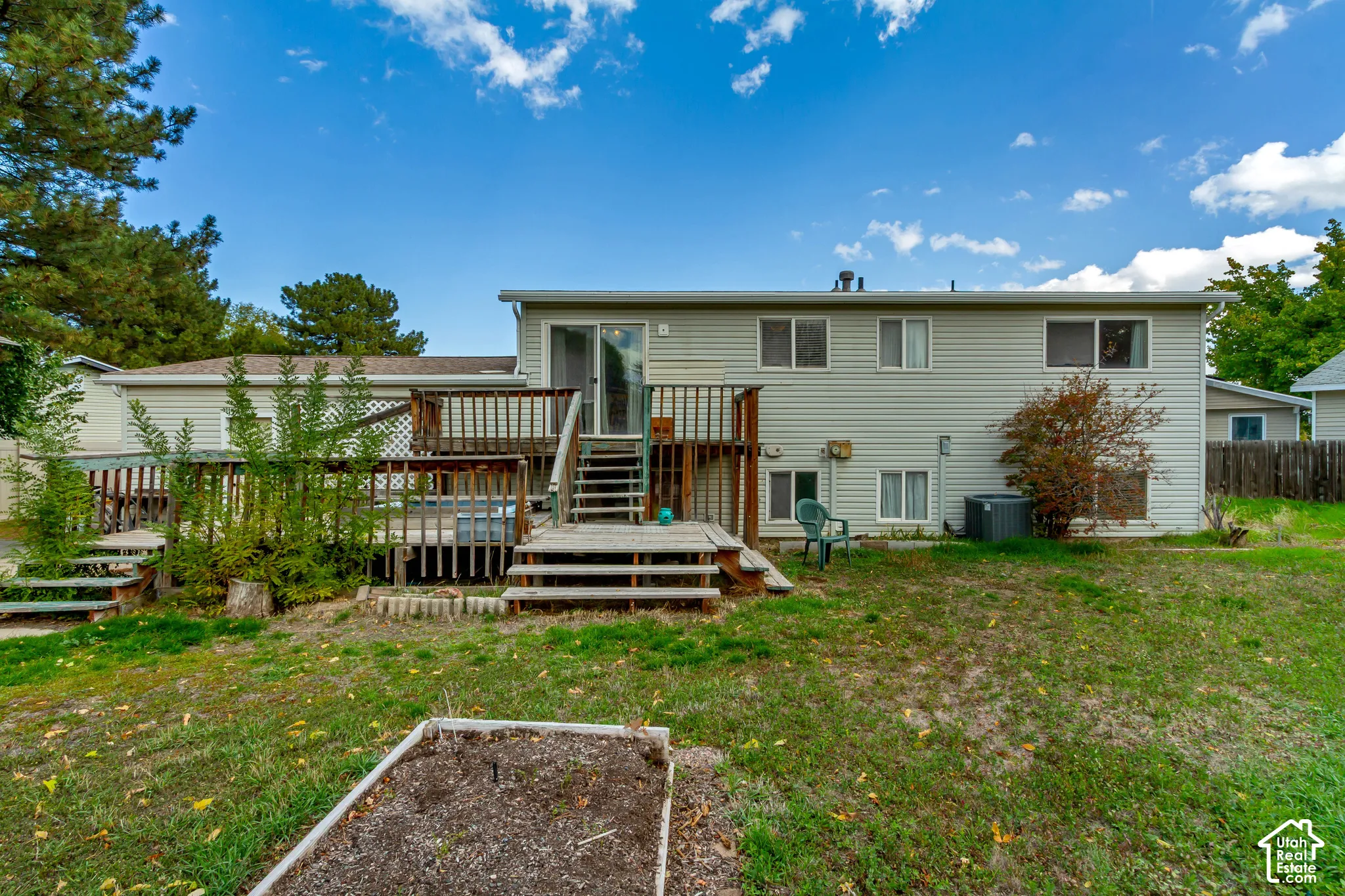 Multi-level wood deck featuring a wooden staircase and privacy railing, siding exterior, and a raised garden bed