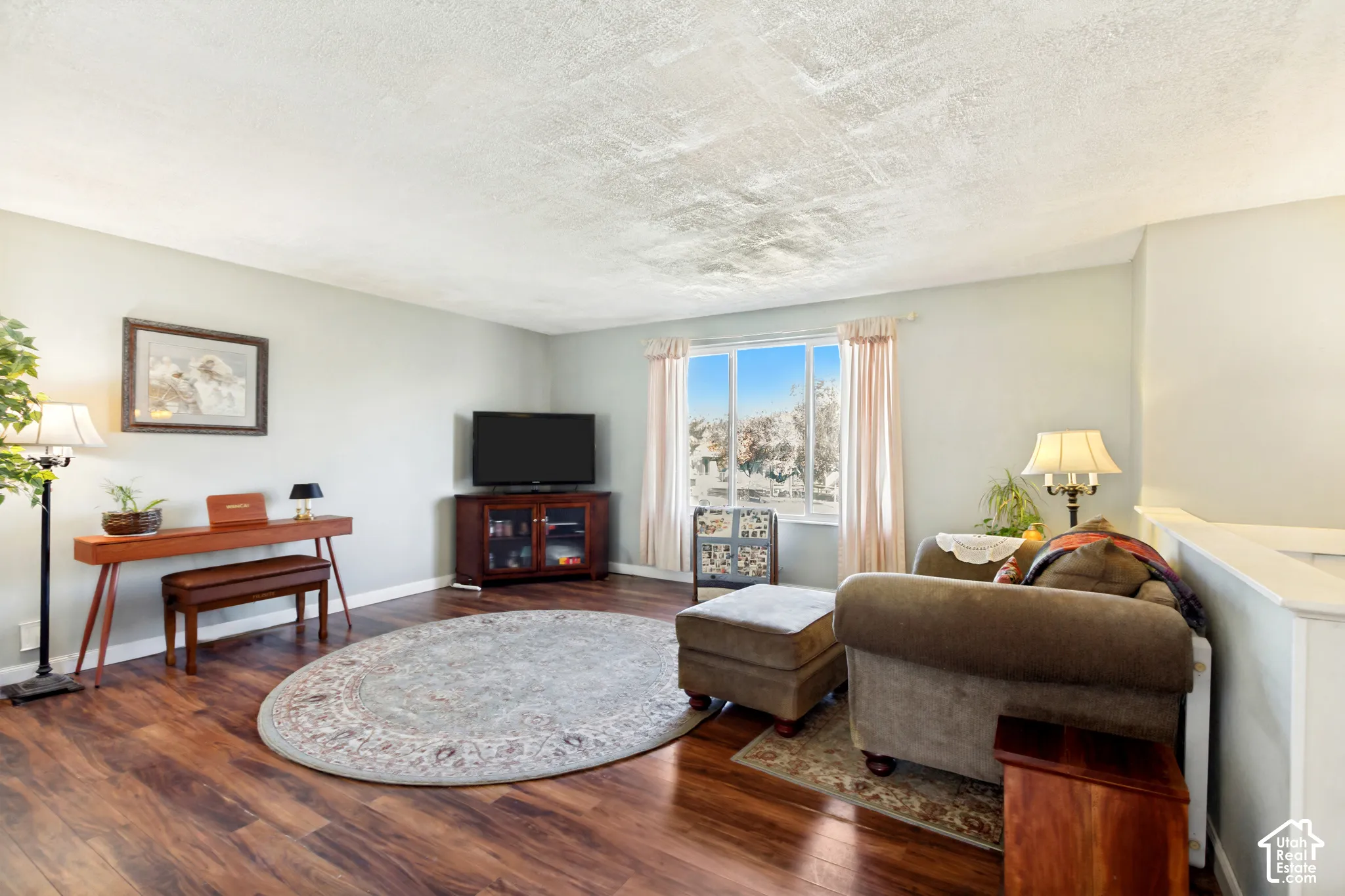Living area featuring wood-finish flooring, a large picture window, and textured ceiling
