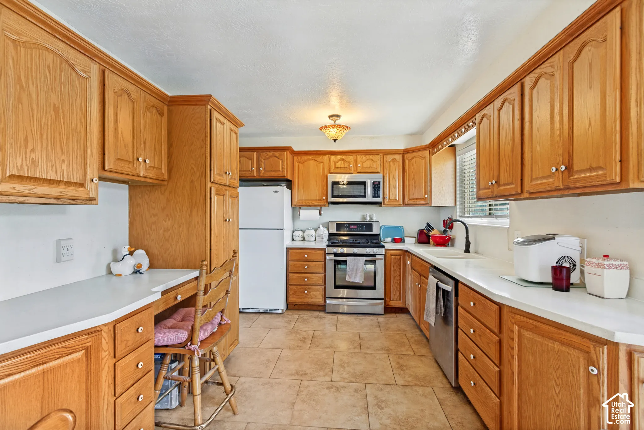 Kitchen featuring wood cabinetry, stone-finish countertops, tile flooring, and integrated stainless steel appliances