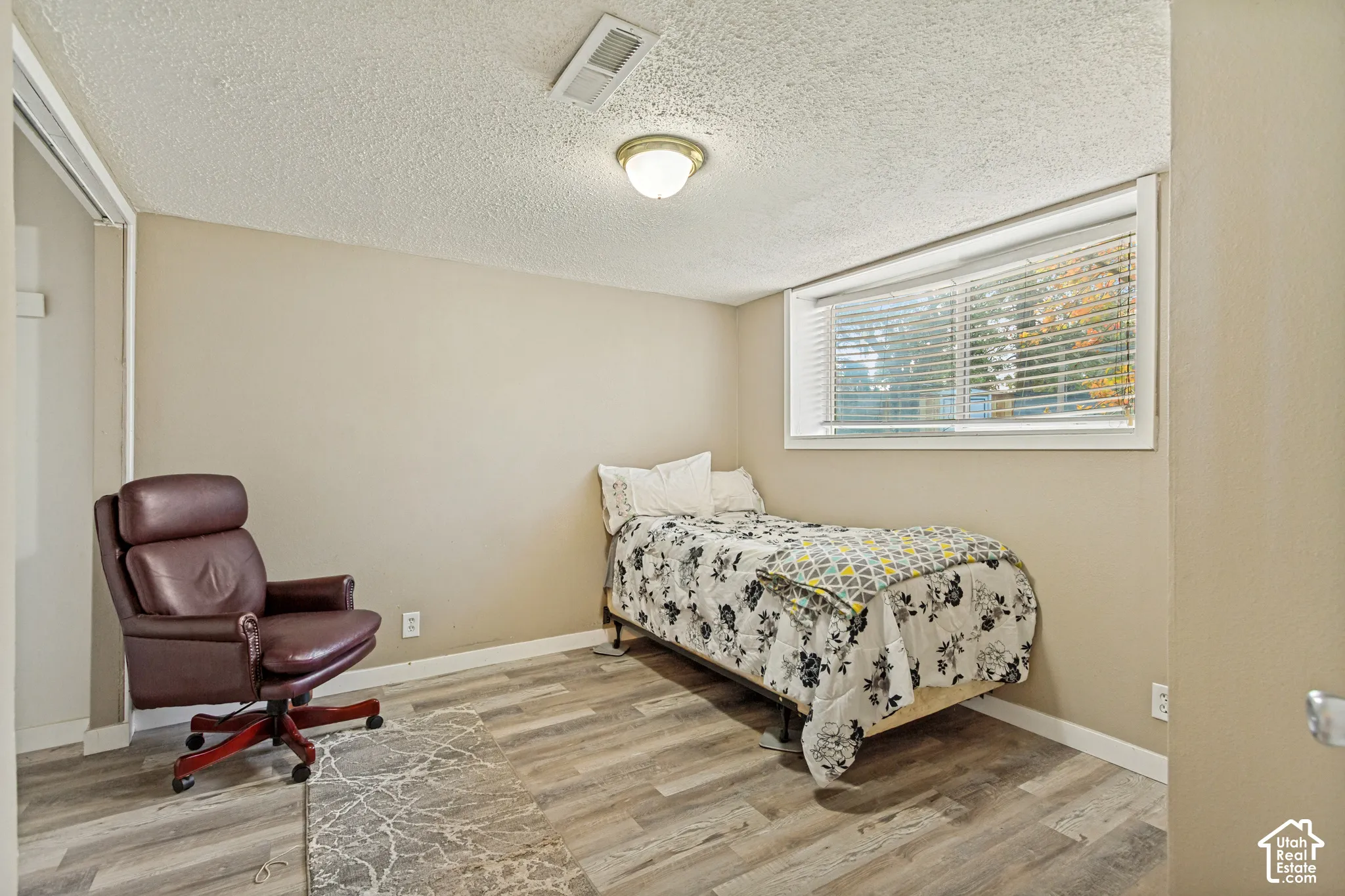 Room featuring wood-finish flooring, a horizontal sliding window, and a flush-mount light fixture