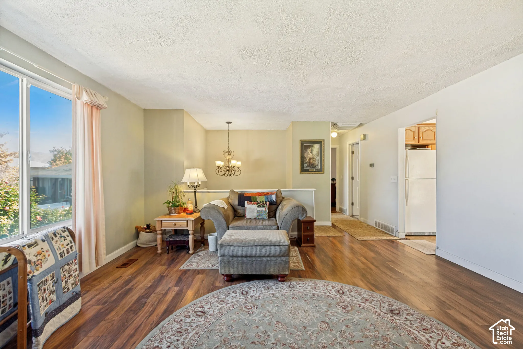Wood-finish flooring, multi-pane window with natural light, and classic hanging chandelier fixture