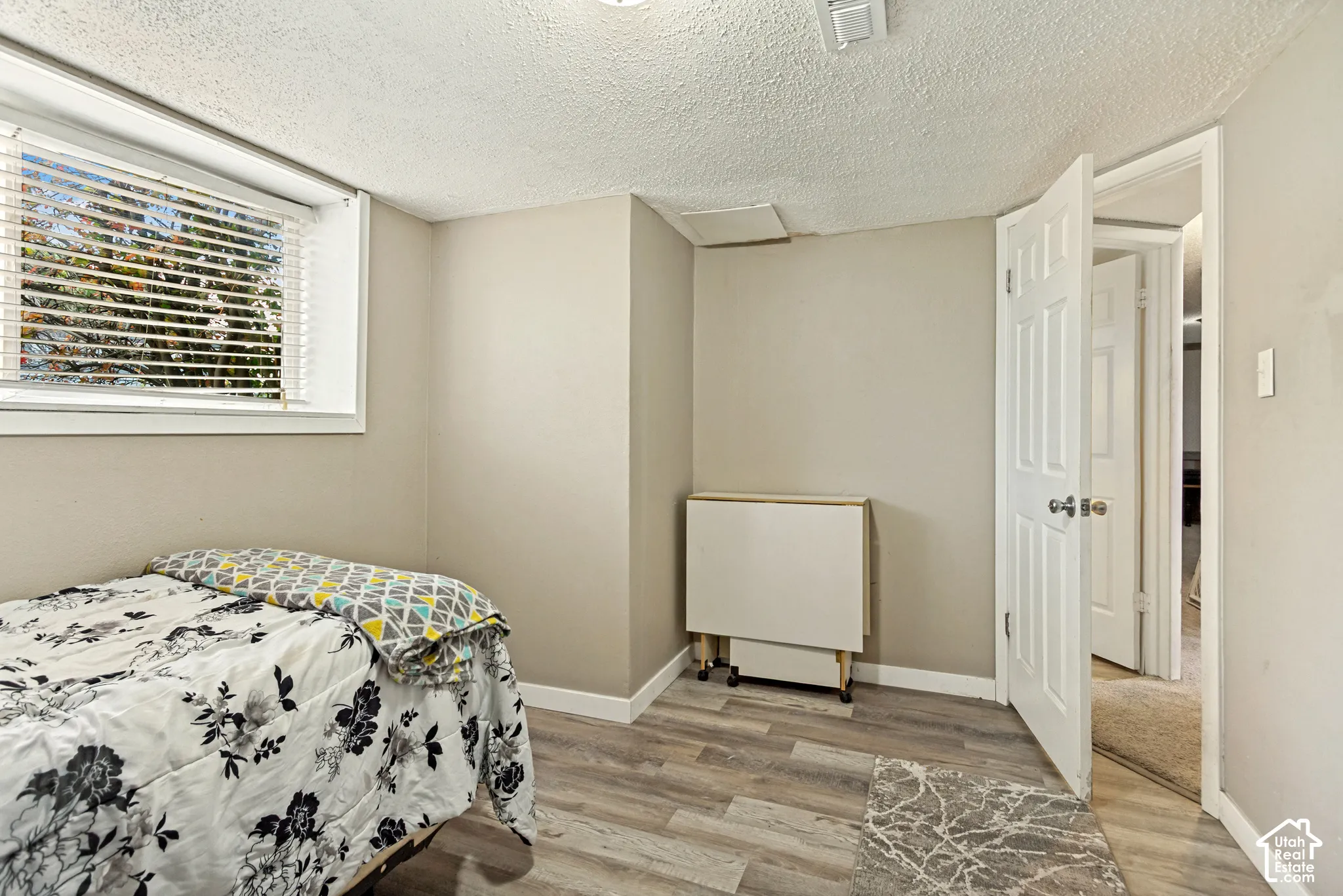 Room featuring neutral wall paint, wood-finish flooring, and a window with horizontal blinds