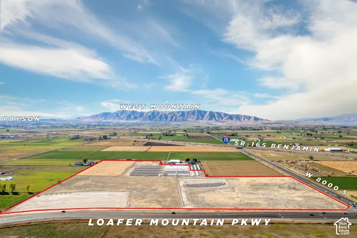 Expansive acreage featuring prominent mountain backdrop, paved road frontage, and onsite greenhouse structures
