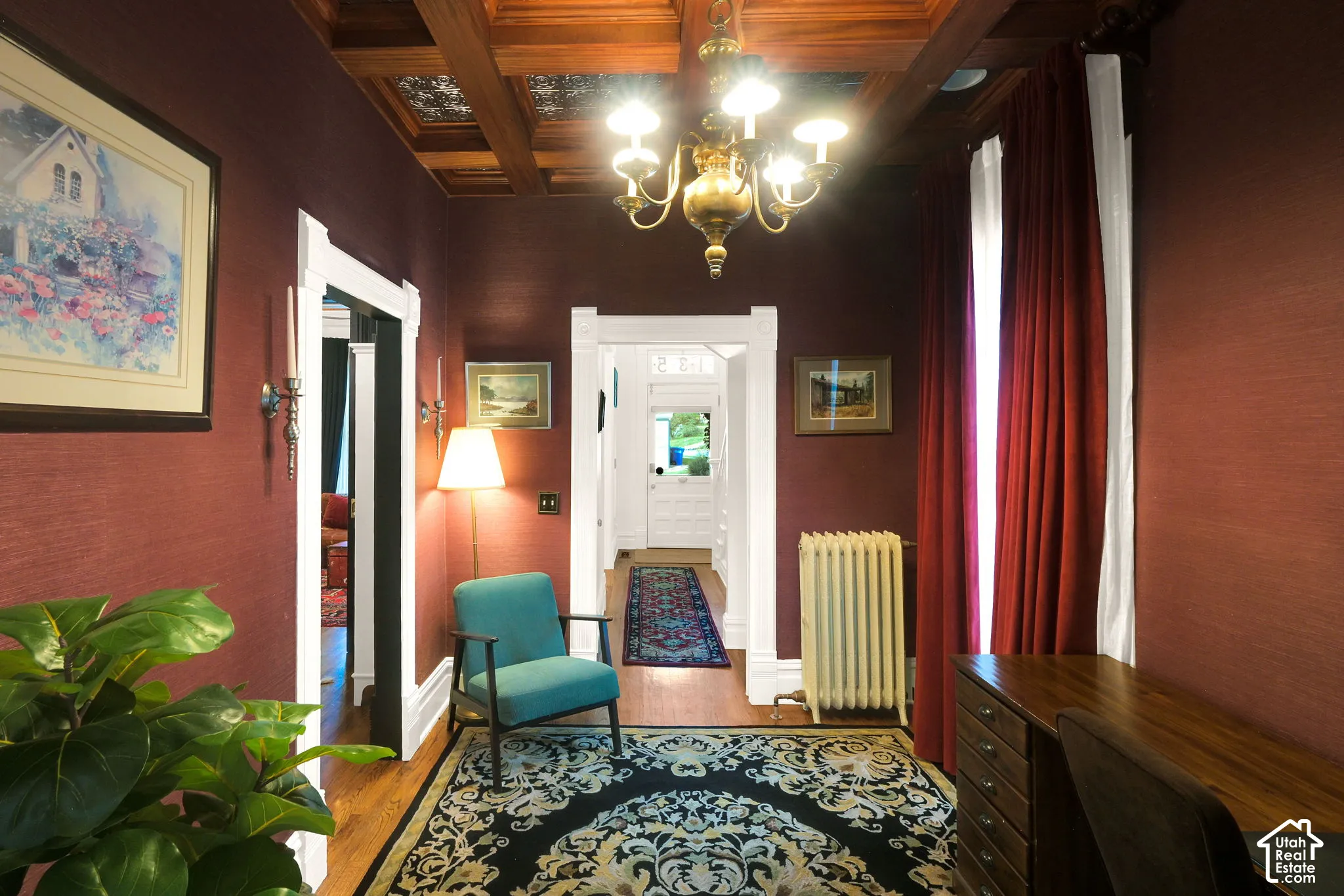 Coffered wood ceiling with recessed metallic detailing, classic chandelier, and white crown molding