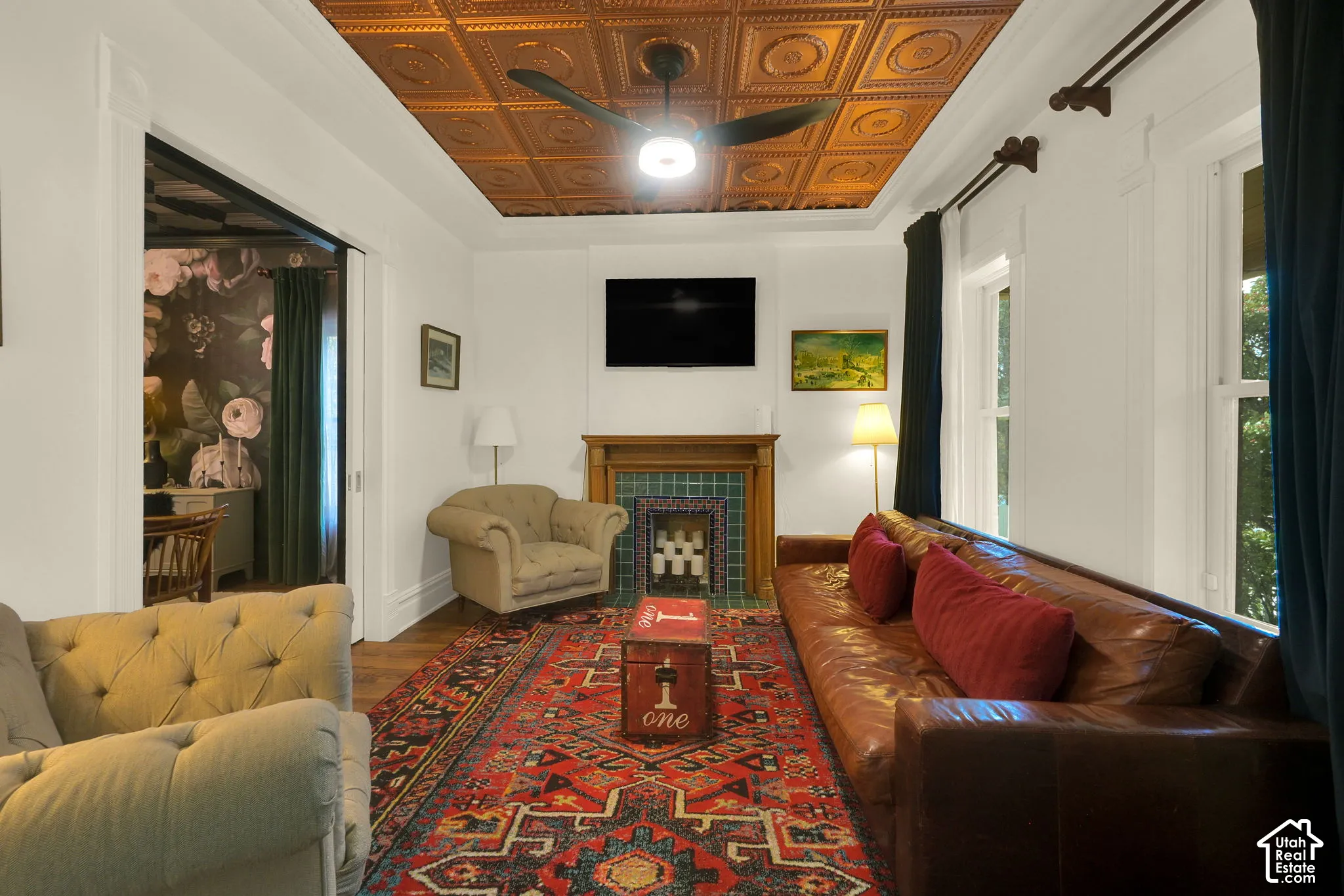 Living space featuring a coffered tin ceiling, wood-finish flooring, and a fireplace with decorative tile surround and a wood mantel