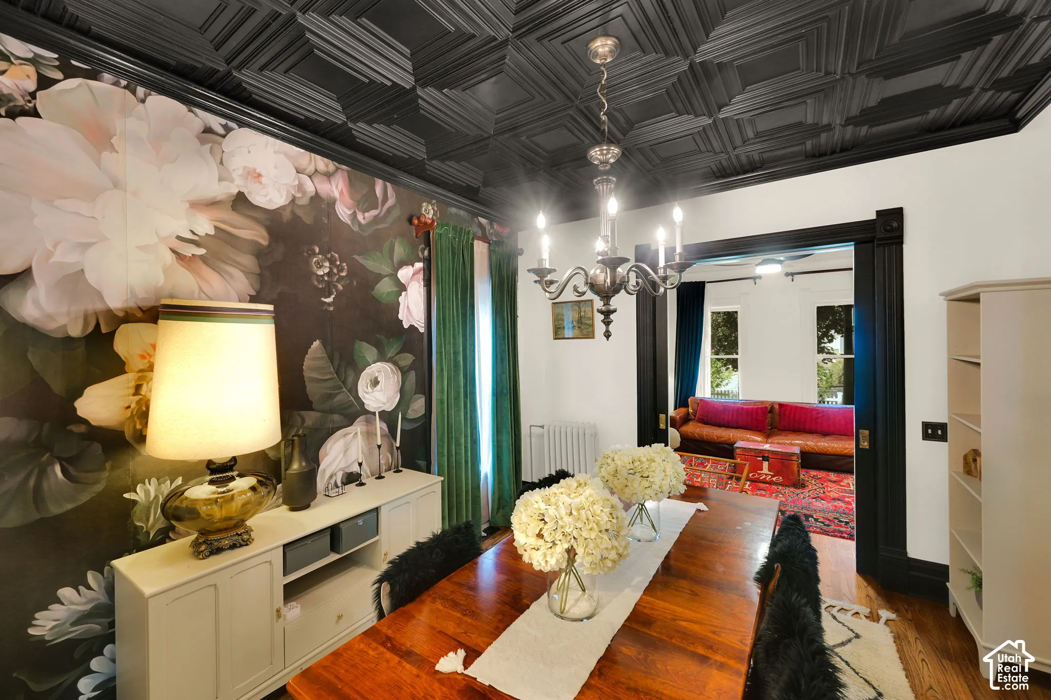 Detailed floral wall mural, black coffered ceiling, traditional multi-arm chandelier, and dark-stained door casing