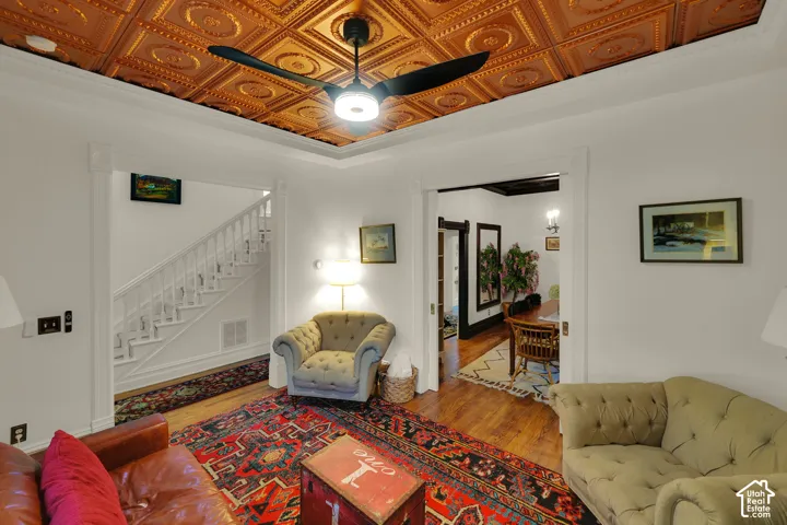 Copper-toned decorative tin ceiling, matte black ceiling fan, wood-finish flooring, and crown molding
