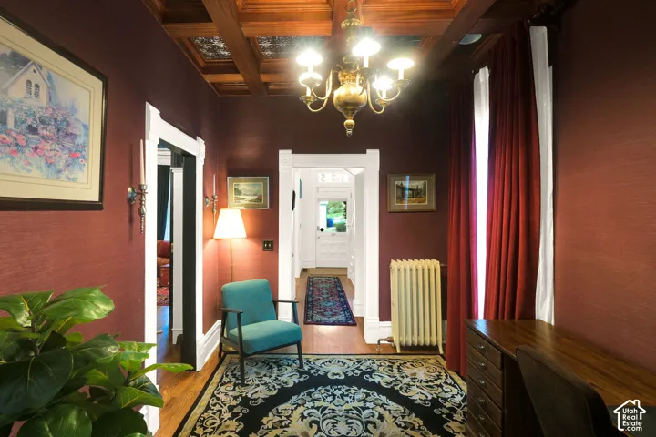Coffered wood ceiling with recessed metallic detailing, classic chandelier, and white crown molding