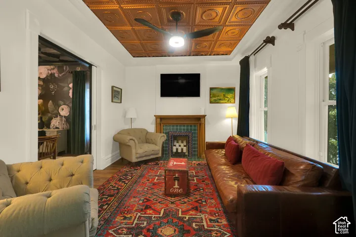 Living space featuring a coffered tin ceiling, wood-finish flooring, and a fireplace with decorative tile surround and a wood mantel