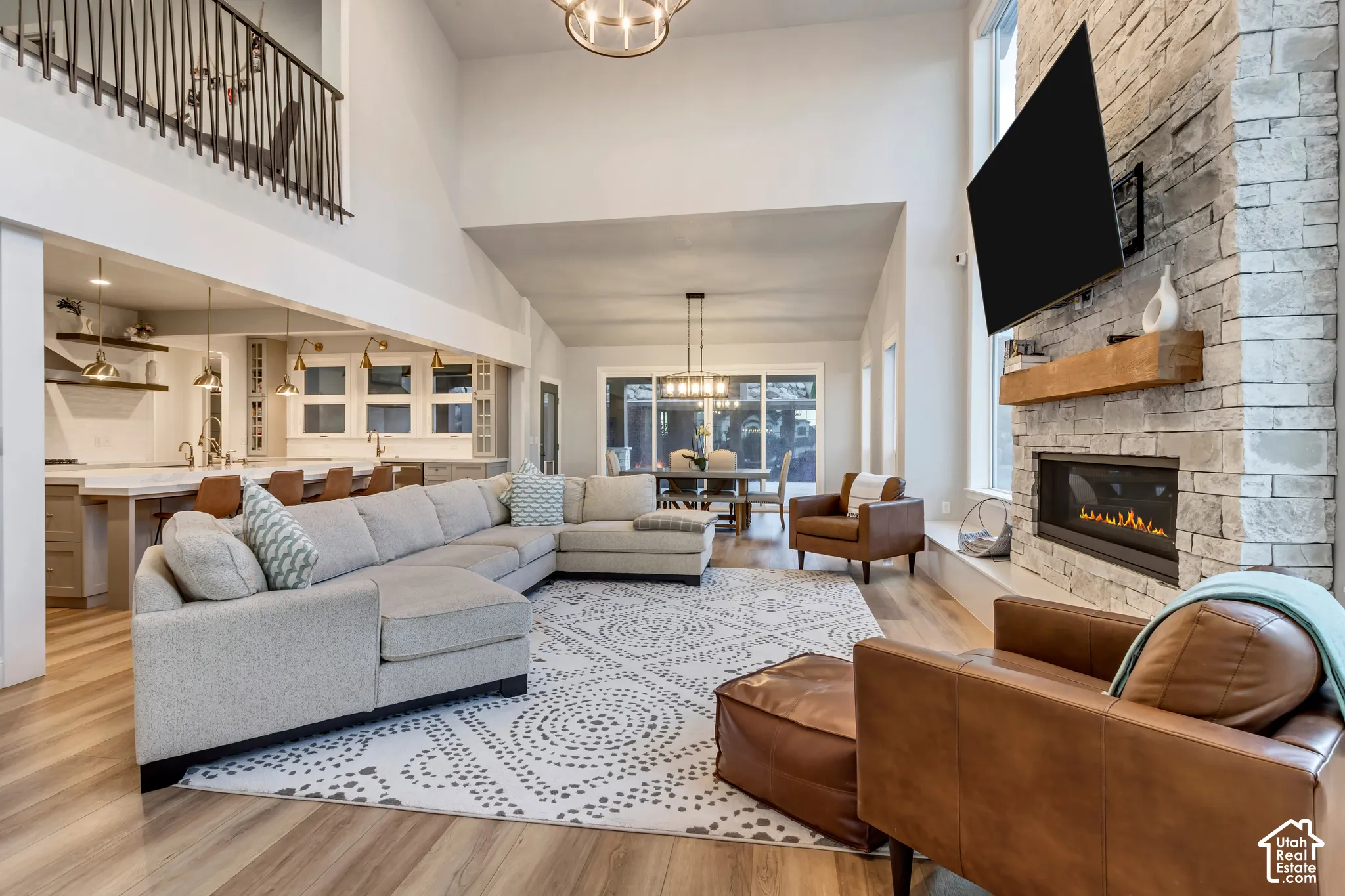 Vaulted ceiling featuring a floor-to-ceiling stacked stone fireplace, wood-finish flooring, and a metal-railing staircase
