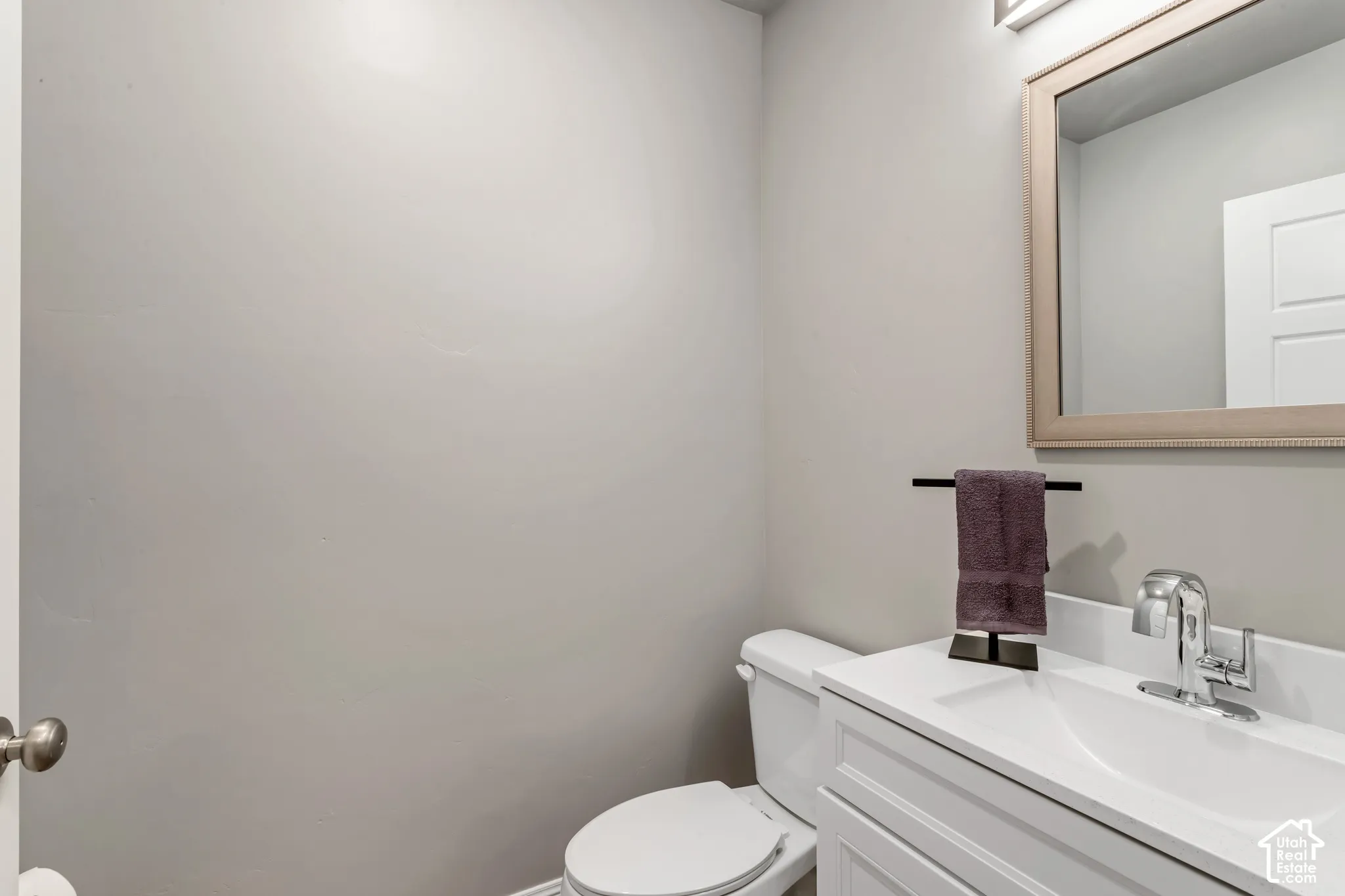 White vanity featuring an integrated sink, polished chrome faucet, and rectangular mirror with a wood-finish frame