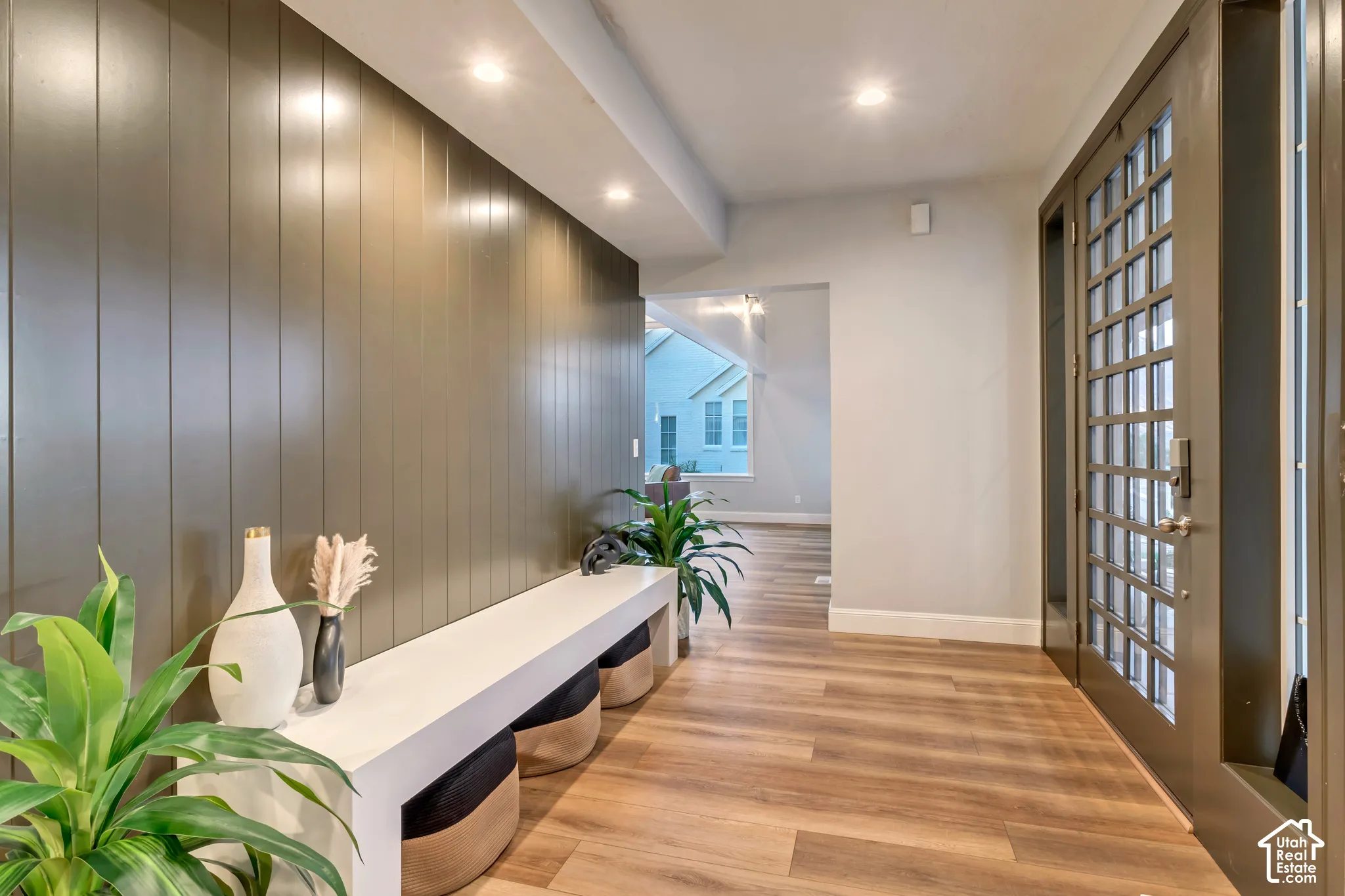 Entryway featuring wood-finish flooring, vertical slat wall paneling, a custom built-in white console shelf, recessed ceiling lighting, and a multi-pane glass entry door