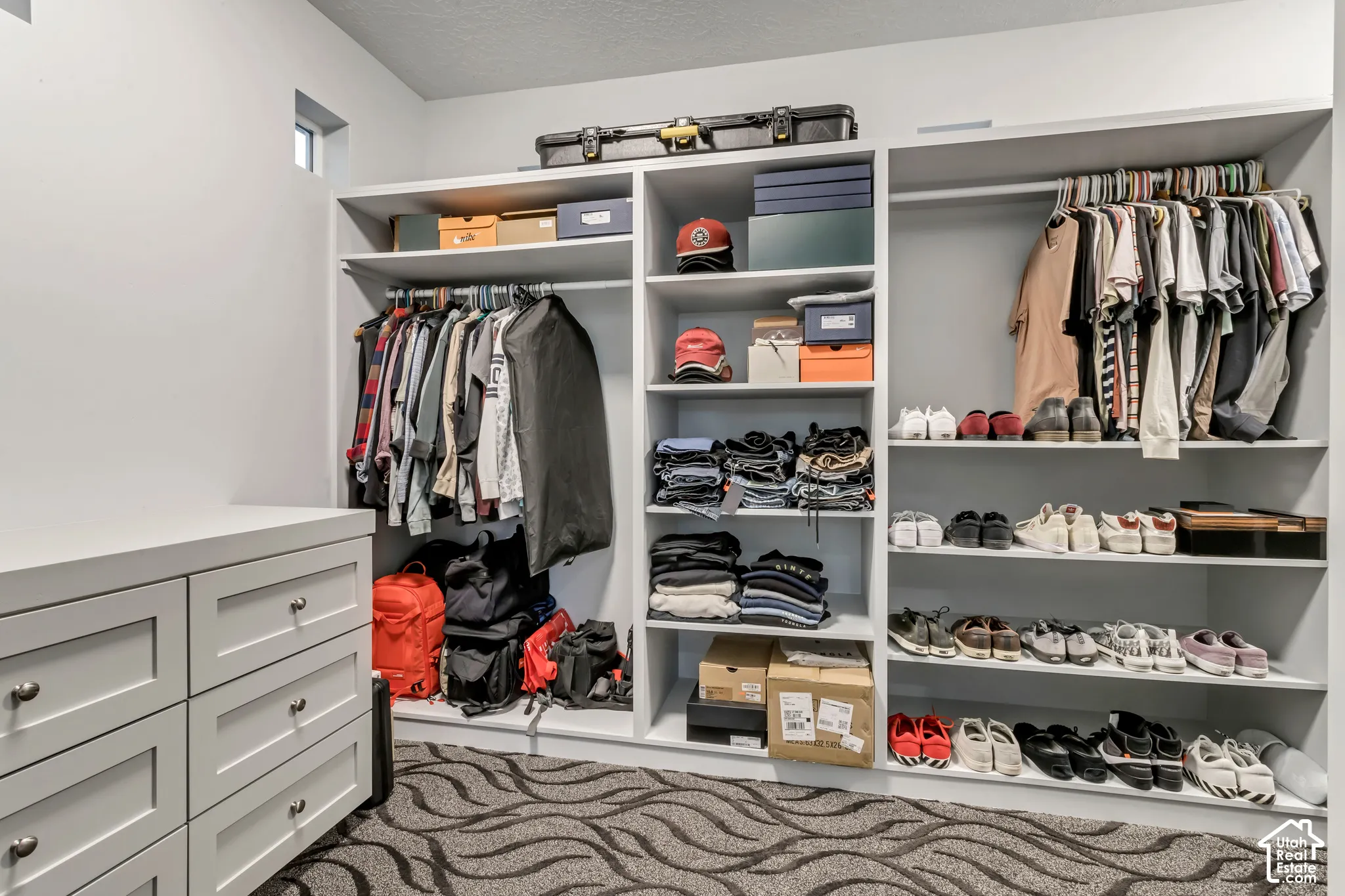 Custom walk-in closet featuring extensive built-in shelving, hanging rods, and a integrated four-drawer storage unit
