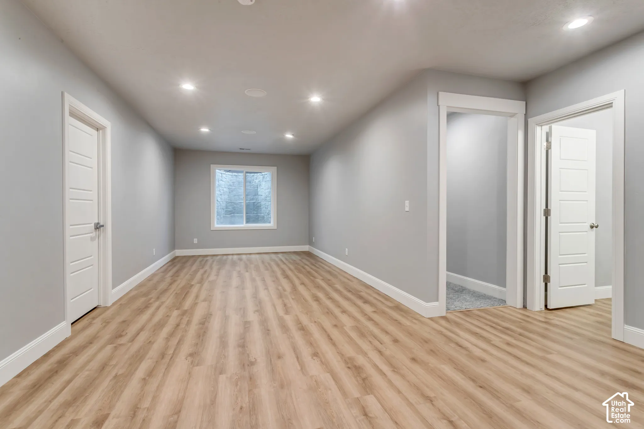 Interior space featuring neutral-toned wall paint, wood-finish flooring, recessed lighting, and white paneled doors