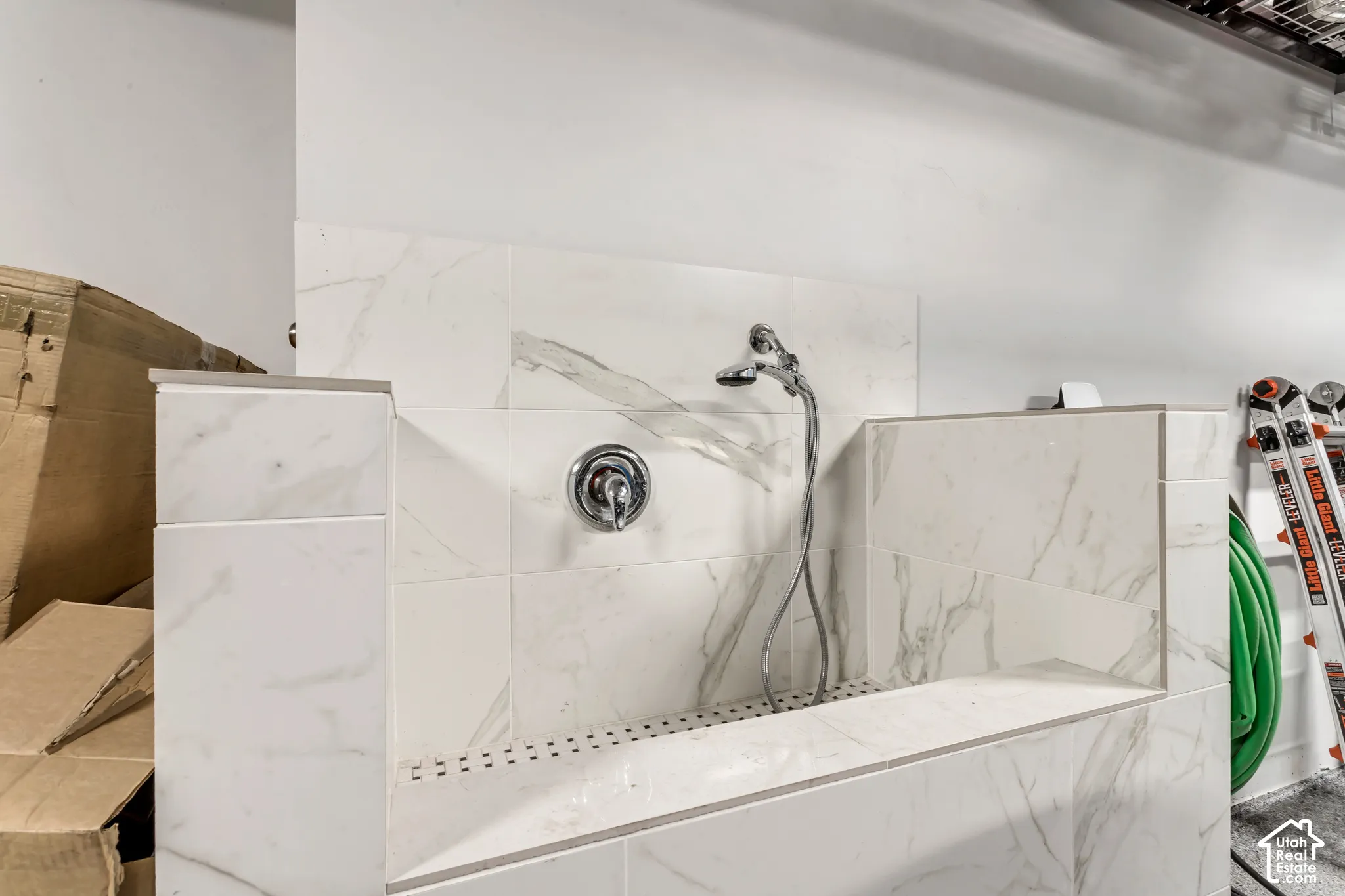 Custom wash station featuring large-format stone-patterned tile, chrome single-handle faucet, and handheld shower sprayer