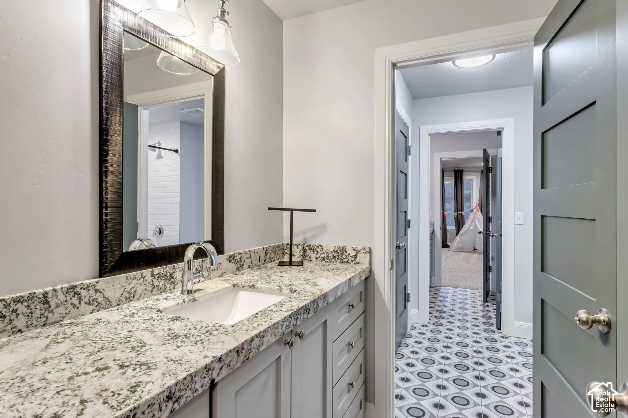 Vanity featuring a stone-look countertop with an integrated rectangular basin, framed mirror, polished chrome faucet, and shaker-style cabinetry