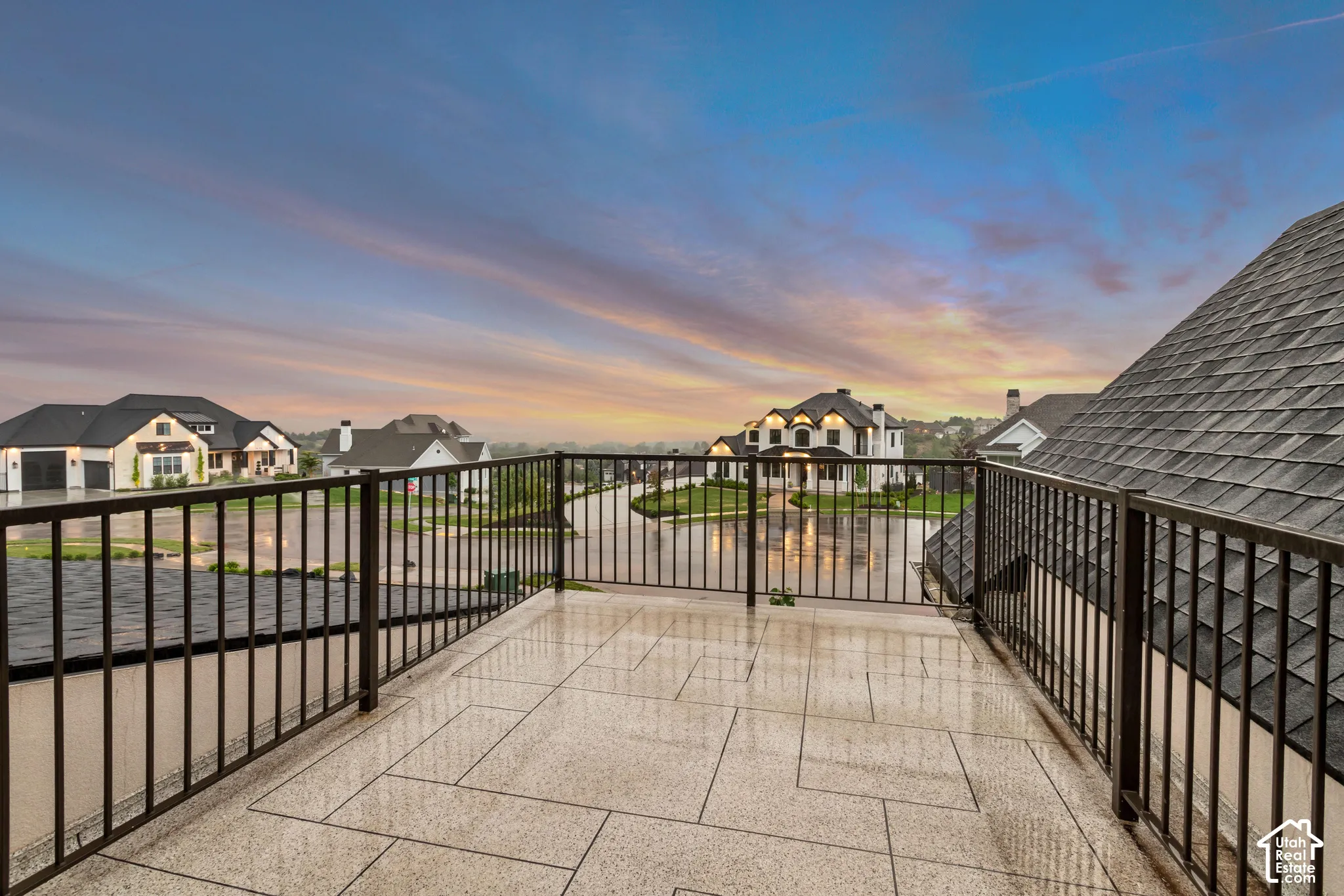 Elevated balcony featuring large-format stone-style tile flooring, decorative metal railings, and wide-reaching outdoor surroundings
