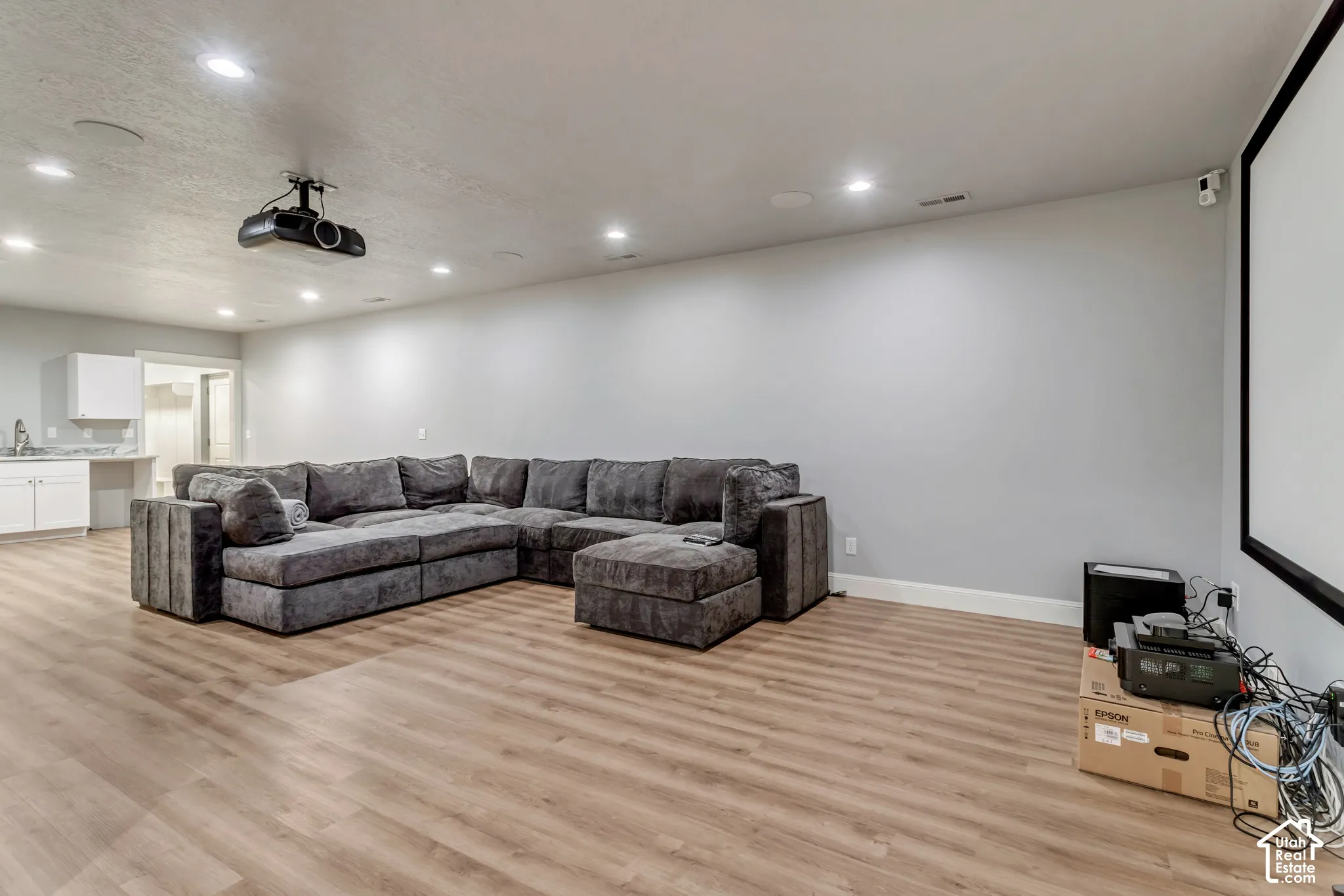 Recessed lighting, wood-finish flooring, ceiling-mounted projector, wall-mounted projection screen, and built-in wet bar cabinetry