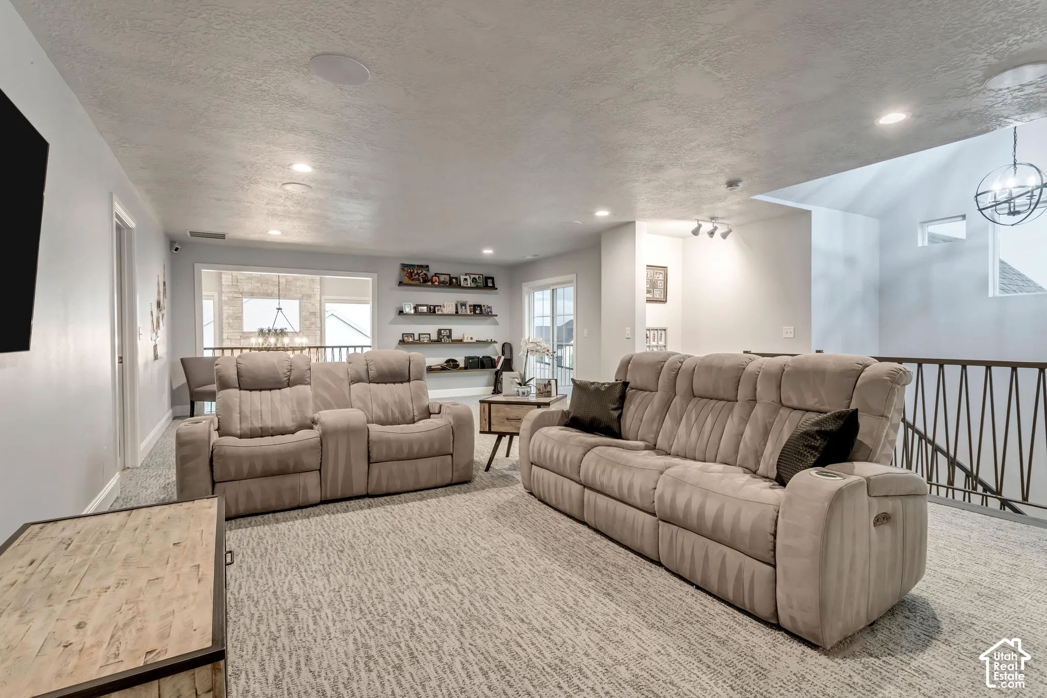 Open-concept space featuring recessed lighting, built-in wall shelving, metal stair railing, and a vaulted ceiling with an industrial-style chandelier