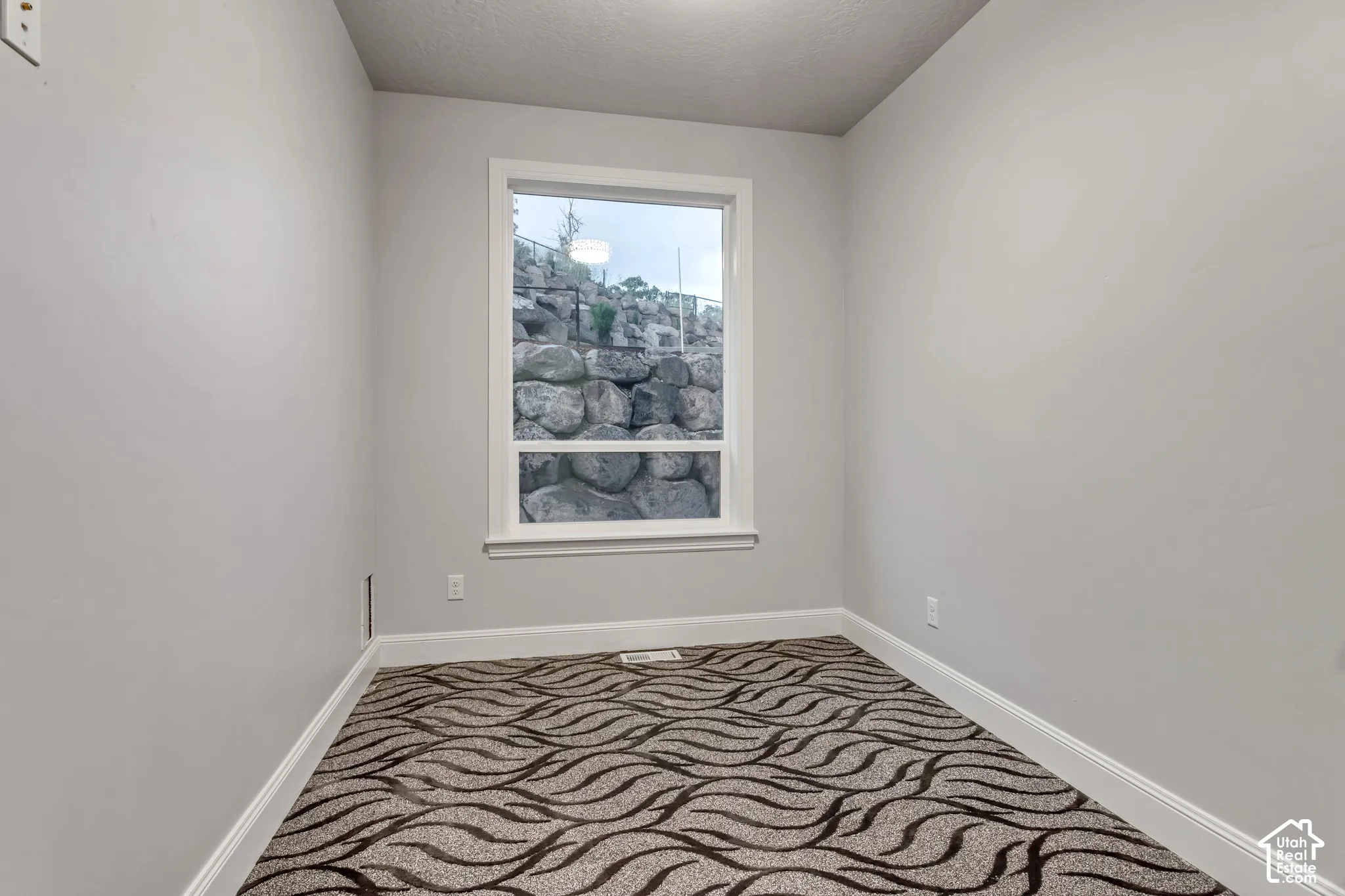 Neutral wall finishes featuring a single window with a stacked rock landscape exterior