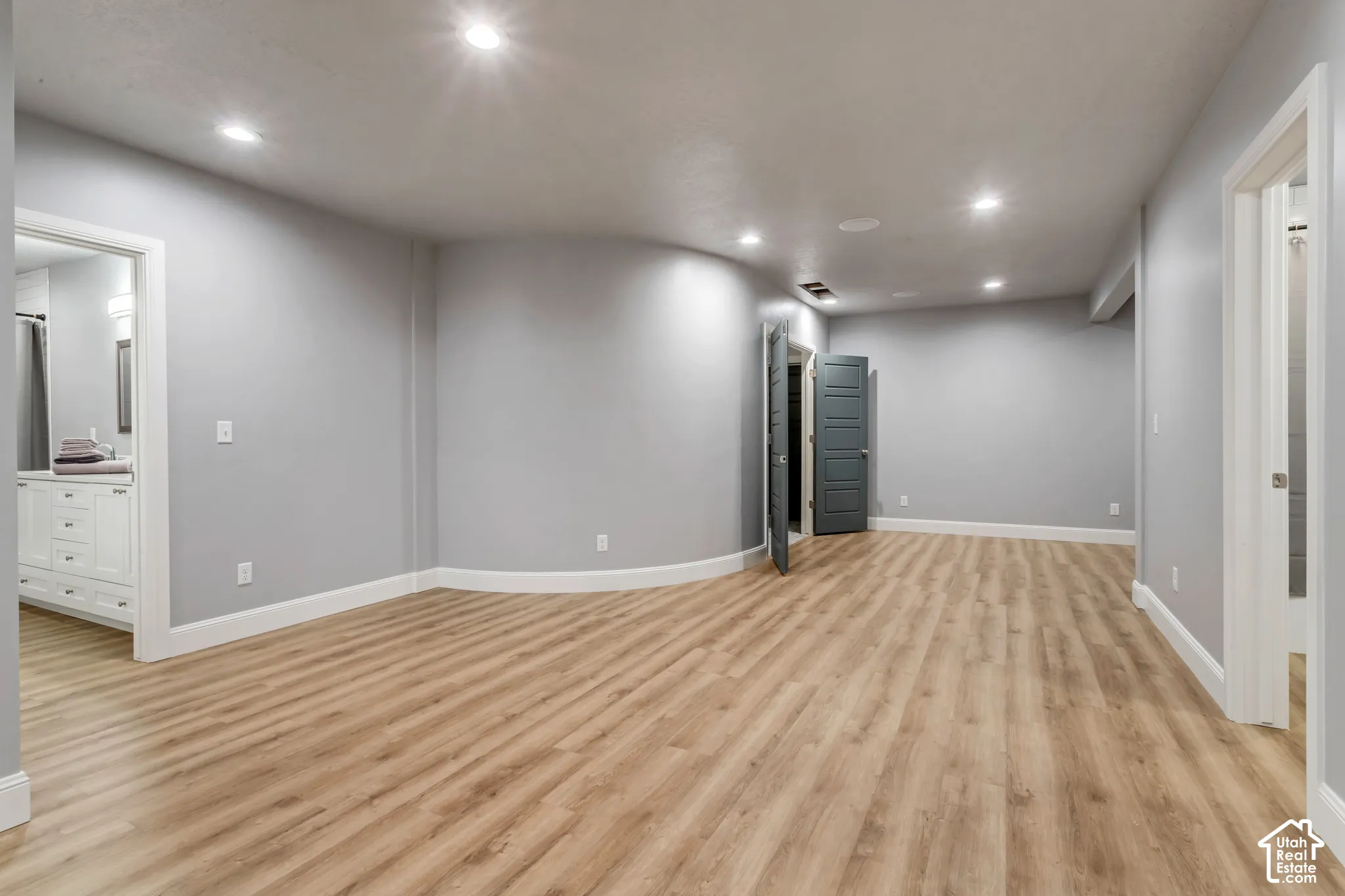 Open-concept room featuring wood-finish flooring, a curved wall, recessed lighting, and multi-panel doors