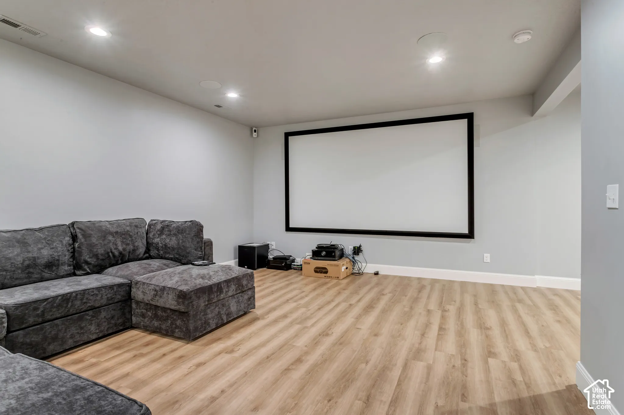 Dedicated media room featuring wood-finish flooring, recessed lighting, and a wall-mounted projection screen