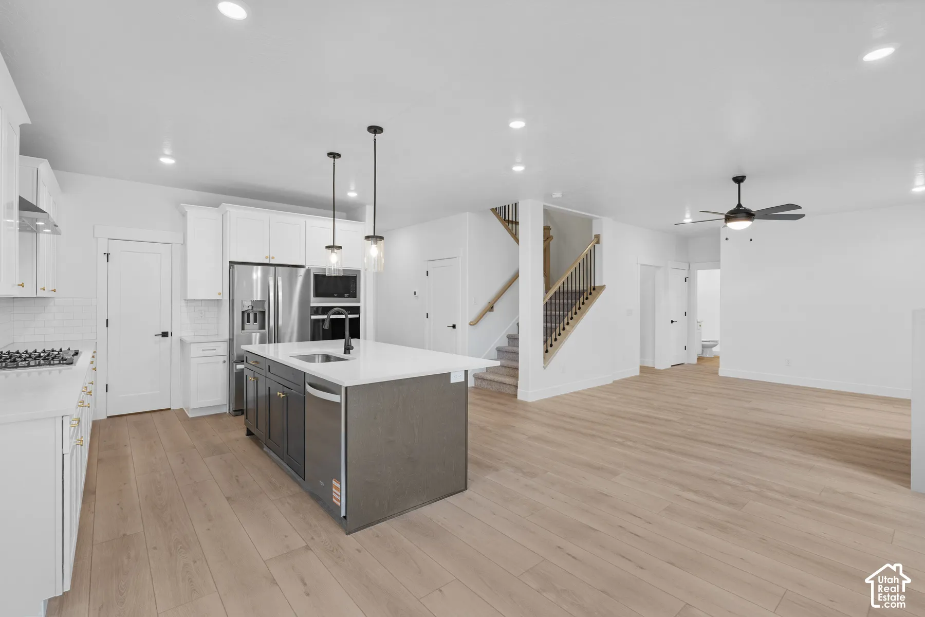 Kitchen featuring white cabinetry, center island with quartz countertop and stainless steel fixtures, recessed lighting, and wood-finish flooring