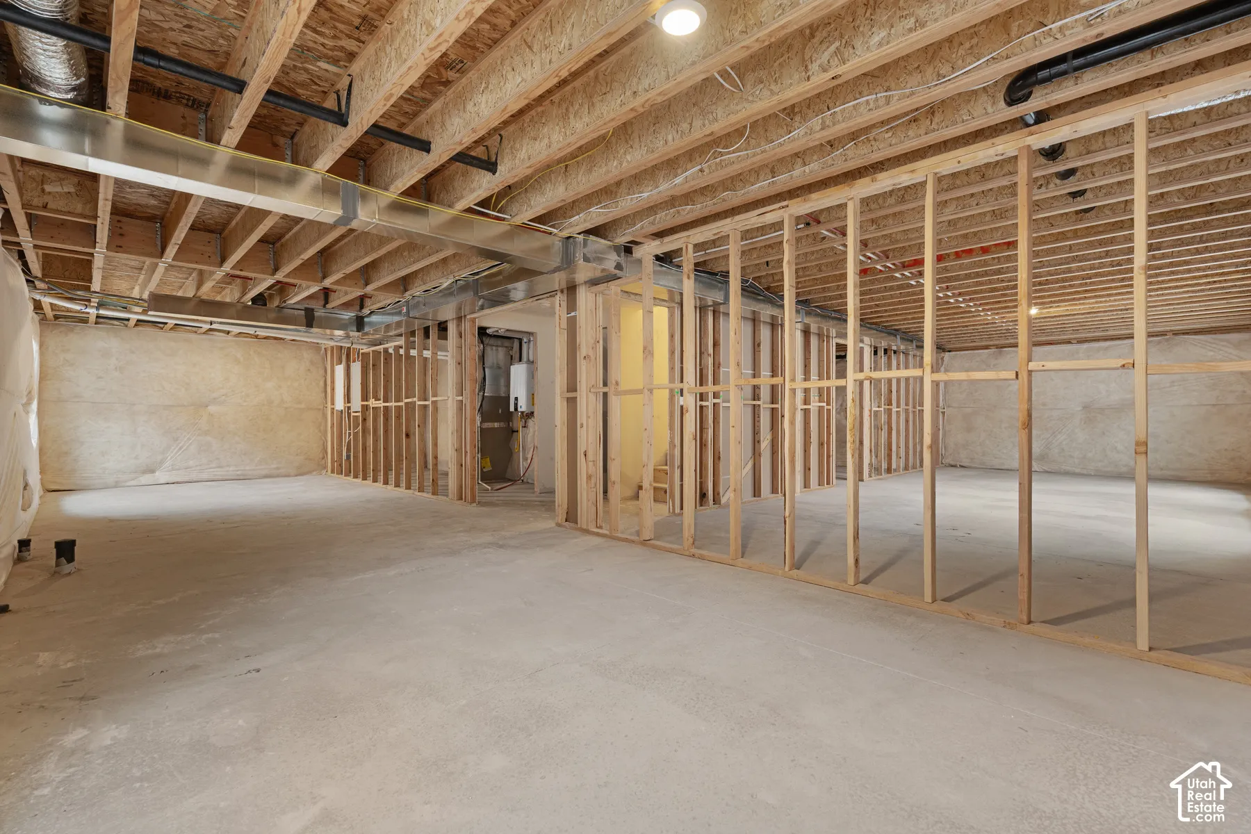 Unfinished space featuring exposed timber framing, concrete flooring, insulated walls, and metal ductwork