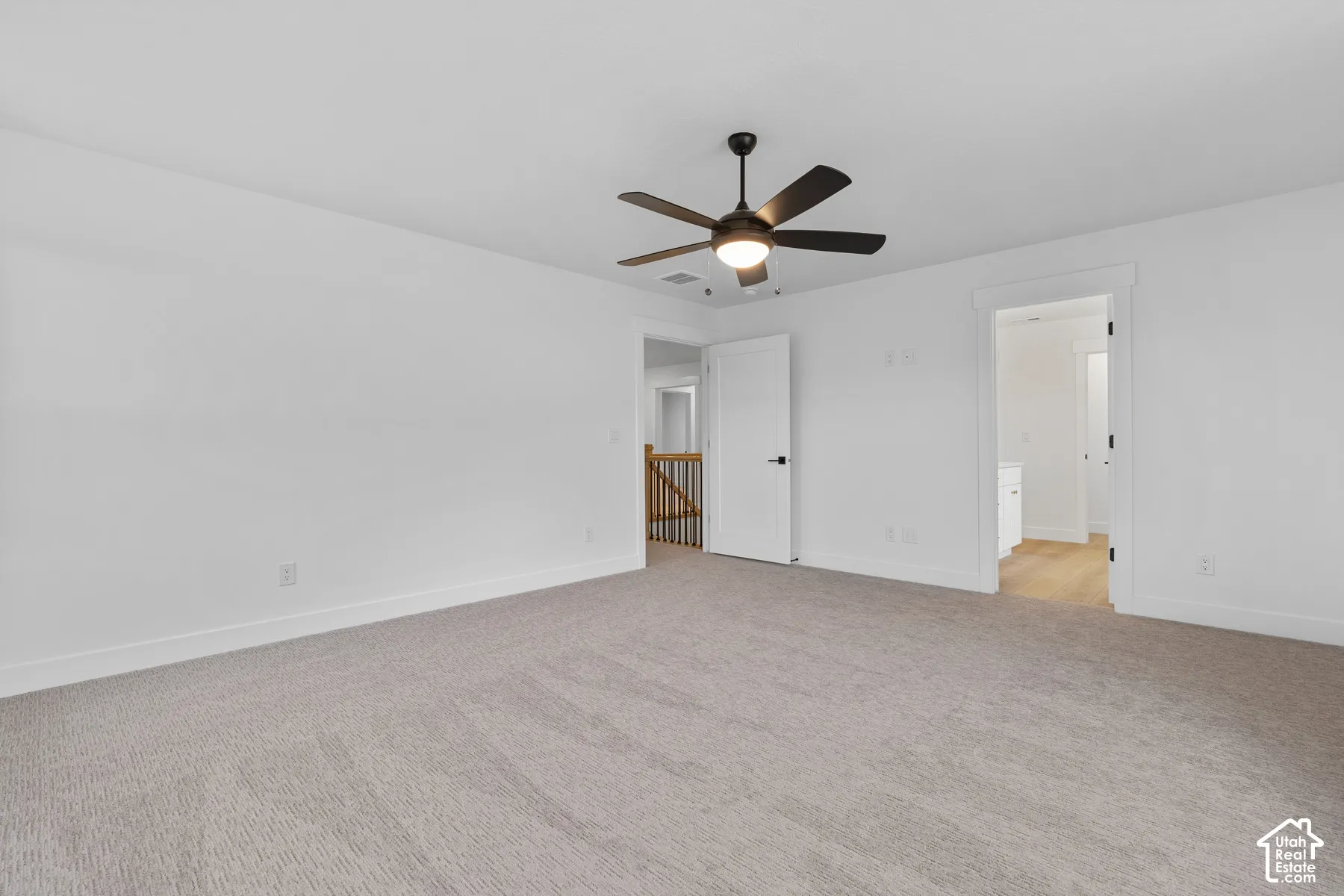 Neutral-toned carpeting, five-blade ceiling fan with integrated lighting, solid-core interior doors, and door casing trim